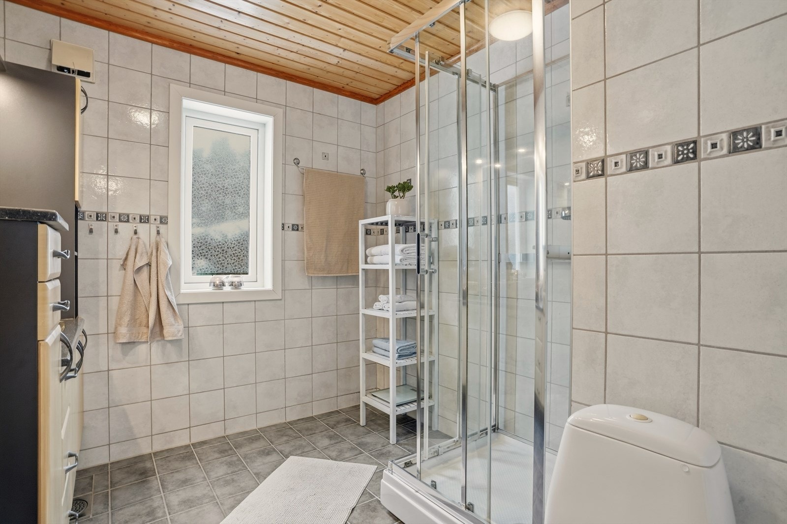 Lyst og funksjonelt bad med dusjkabinett og vindu som gir naturlig dagslys. Galleribilde