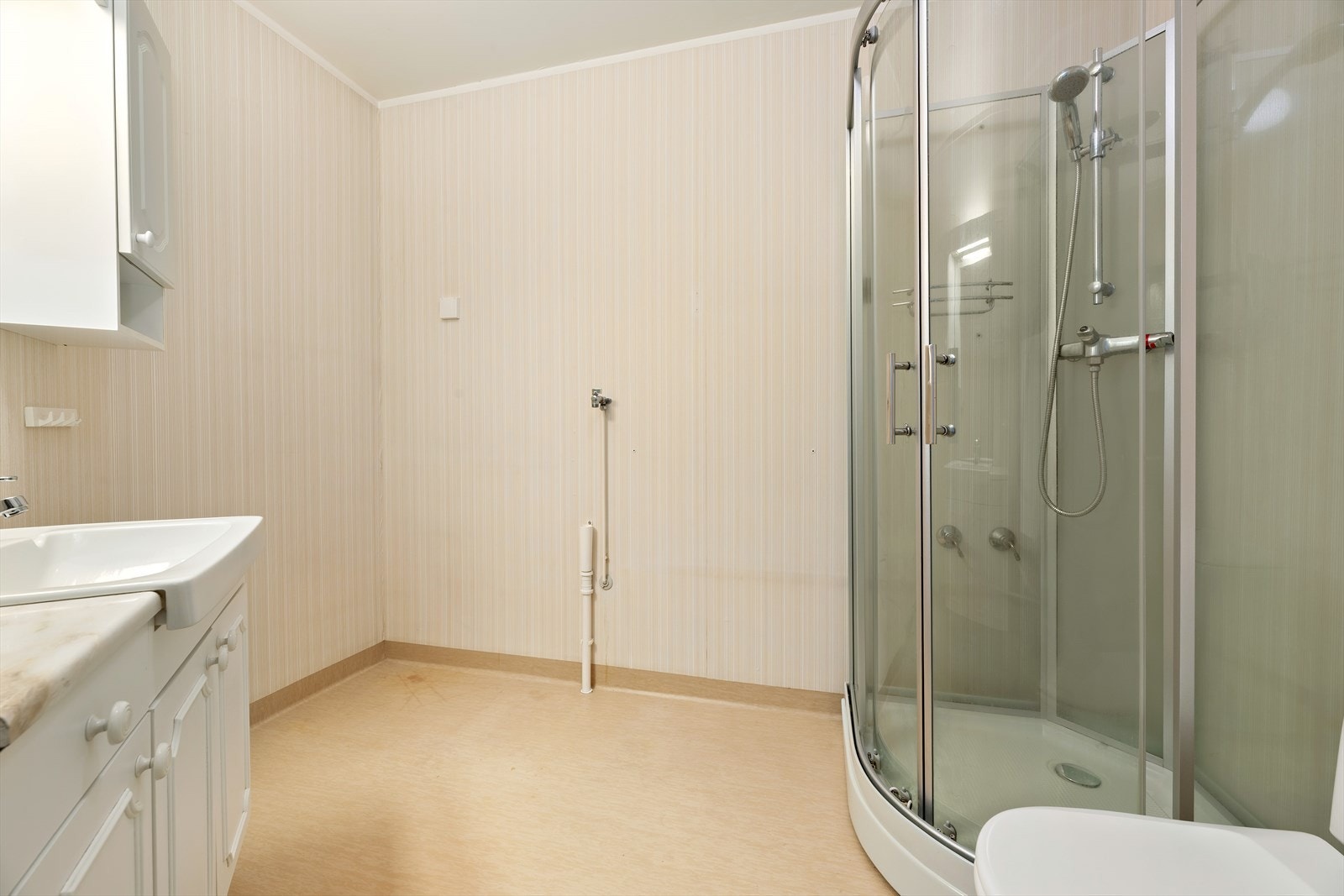 Romslig bad/WC. Dusjkabinett, toalett og innredning med servant. Badet trenger oppgaradering. Galleribilde