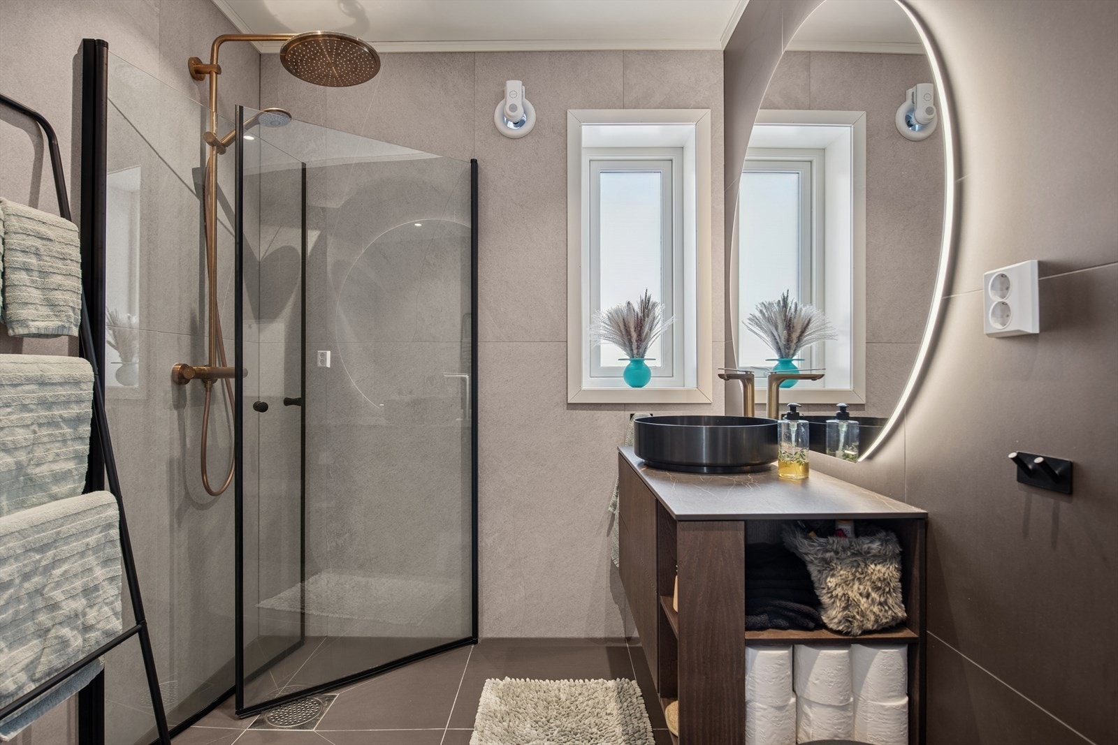 Badet fremstår moderne og delikat, med flislagte vegger og gulv. I gulvet er det elektriske varmekabler som er WiFi-styrte. Rommet har stilrene materialvalg kombinert med elegante gullfargede detaljer som gir et eksklusivt preg. Galleribilde