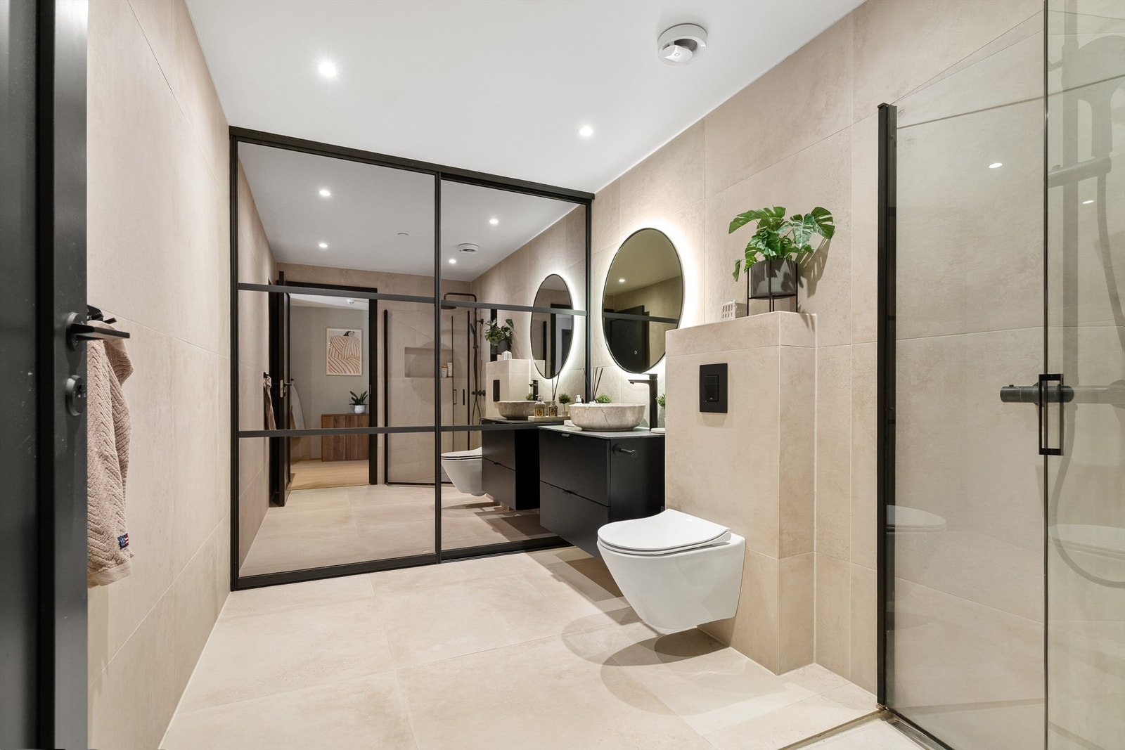 Innholdsrikt og flislagt bad med gulvvarme. Bak skyvedørsgarderobe skjuler det seg både opplegg til vaskemaskin/tørketrommel, ekstra oppbevaring og klesoppheng. Galleribilde