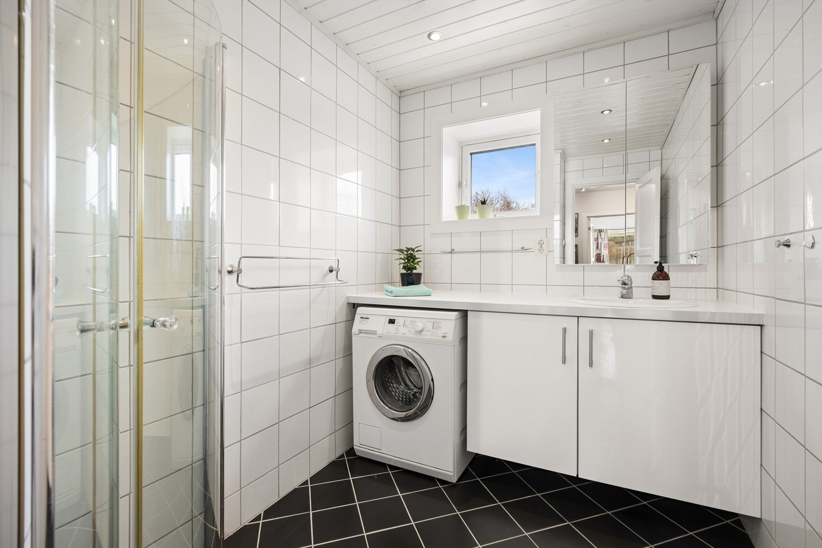 Bad med servantinnredning, dusjhjørne og opplegg for vaskemaskin. Galleribilde