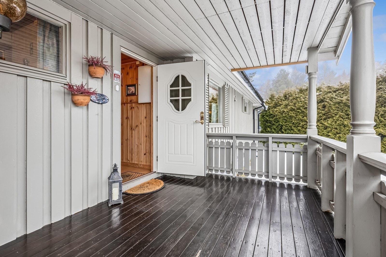 Et overbygd inngangsparti med en solid, malt ytterdør ønsker velkommen inn. Galleribilde