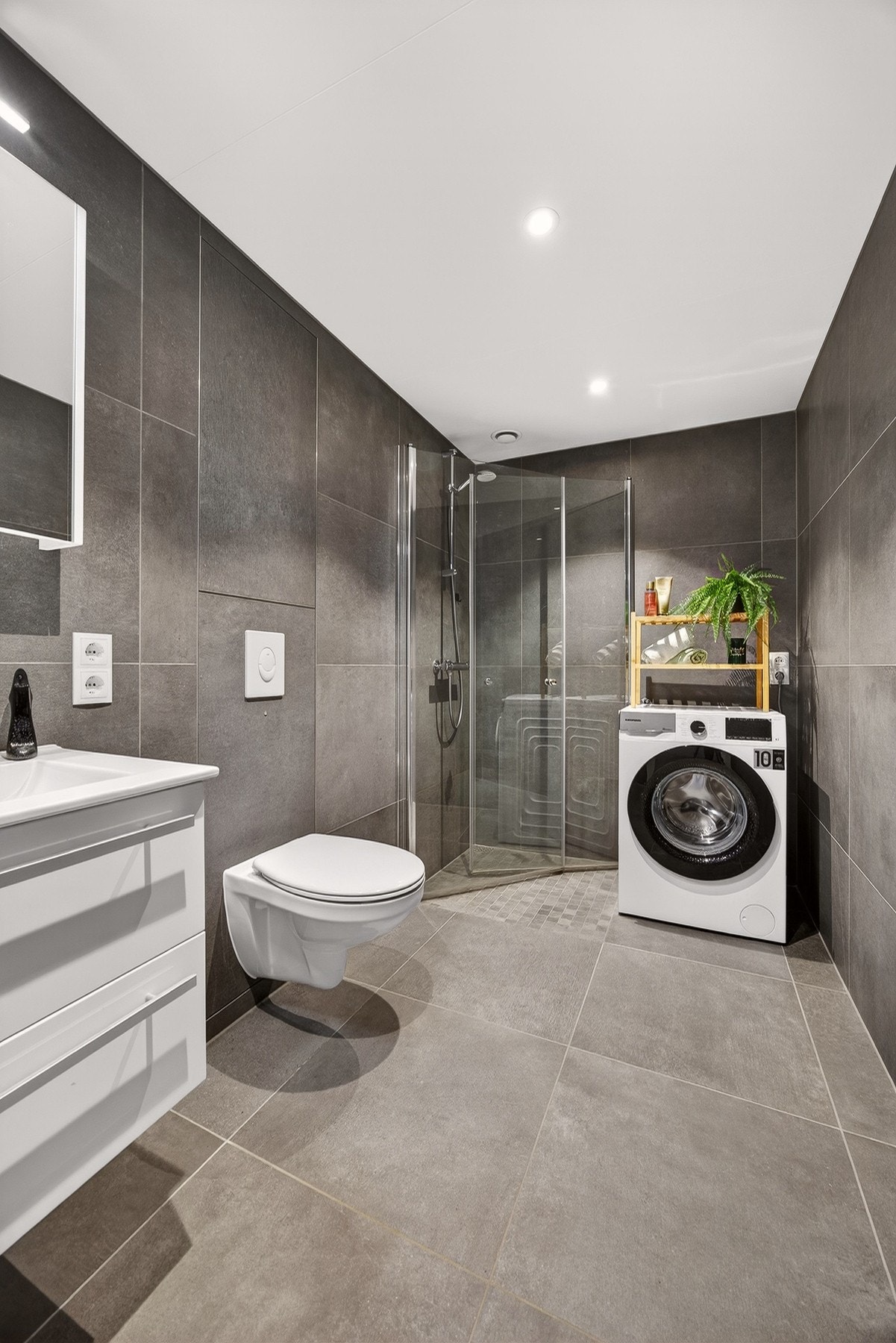 Separat dusjsone med hånddusj og innfellbare dusjvegger i glass. Det er opplegg og plass for vaskemaskin og tørketrommel i vaskesøyle. Galleribilde