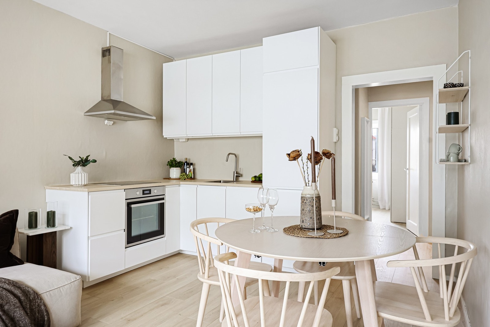 Pent kjøkken fra 2024 innredet med hvite, grepsfrie fronter og overskap med benkebelysning. Galleribilde