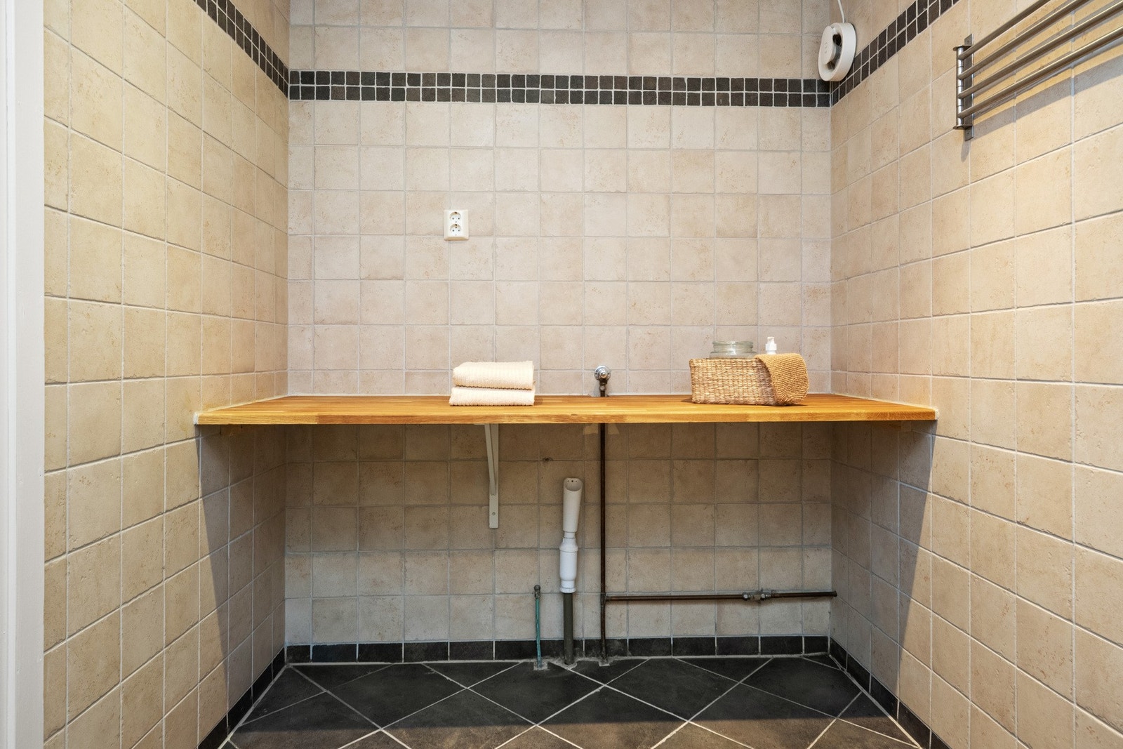 Langs den ene veggen er det etablert en praktisk benkeplate med opplegg for vaskemaskin og plass til tørketrommel under. Galleribilde