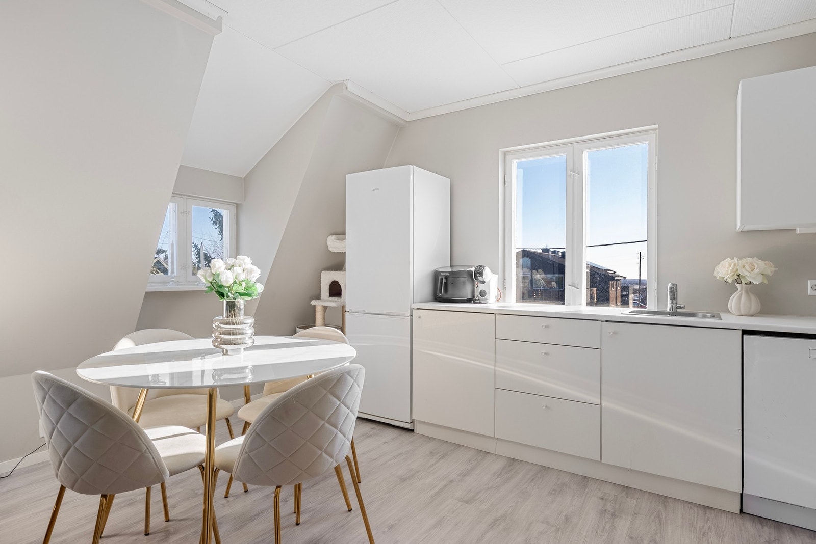 Et lyst og nøytralt kjøkken med slette fronter som harmonerer fint med det lyse rommet Galleribilde