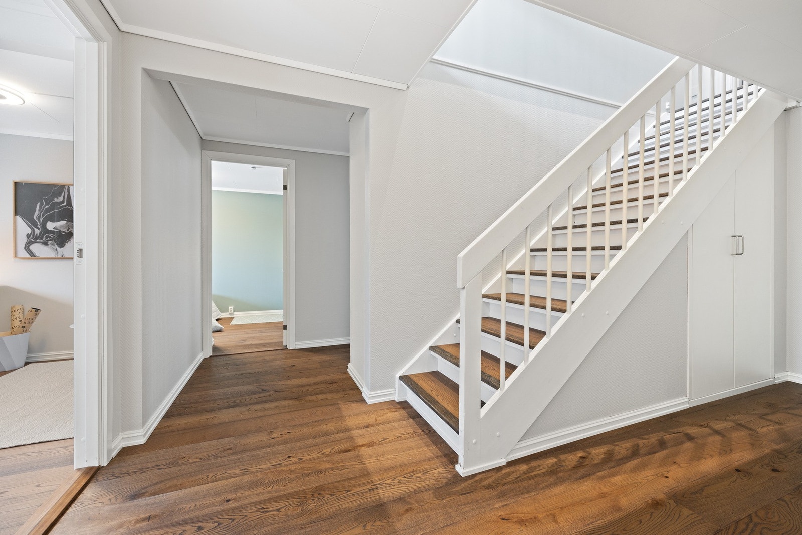 Gang/hall i u. etasje med trapp og praktisk lagringsplass i skap under trappen. Det er gulvvarme i alle oppholdsrom (kjellerstue, soverom, hall og entré/kontor) i denne etasjen. Galleribilde