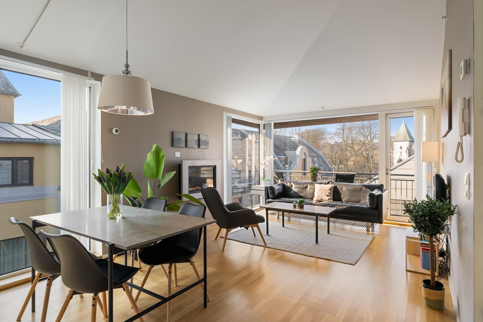 Luftig stue og kjøkken i åpen løsning med god takhøyde og vinduer fra gulv til tak Galleribilde