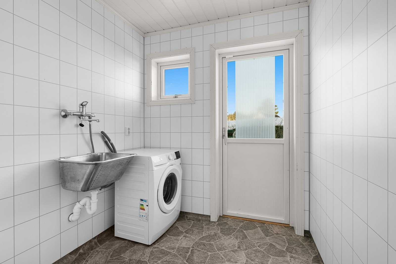 Vaskerom med vaskekum og opplegg for vaskemaskin. Utgang til hage. Galleribilde