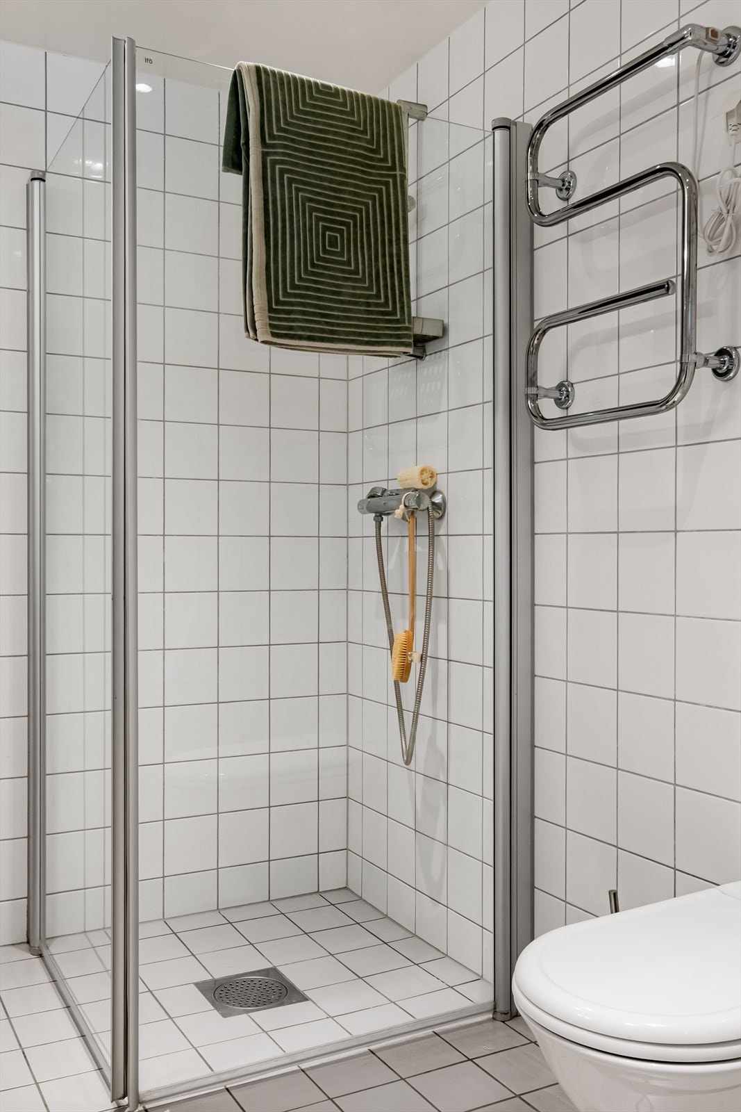 Dusjen er plassert i hjørnet og har håndholdt dusjarmatur samt dusjvegger. Galleribilde