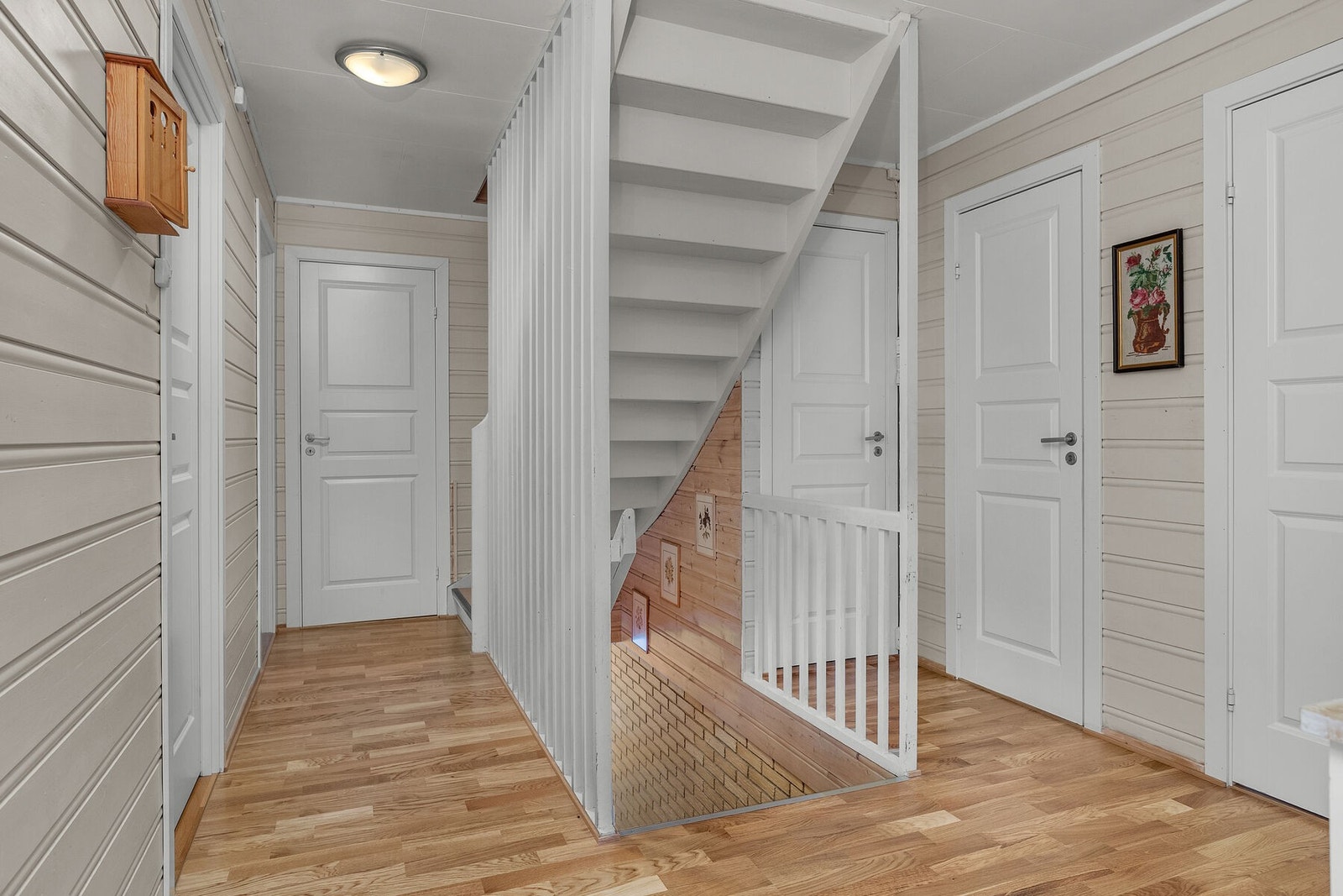 Gang i 1. etasje med trapper mellom etasjene og naturlig adkomst til to soverom, bad, toalettrom, bod, kjøkken og stue. Galleribilde