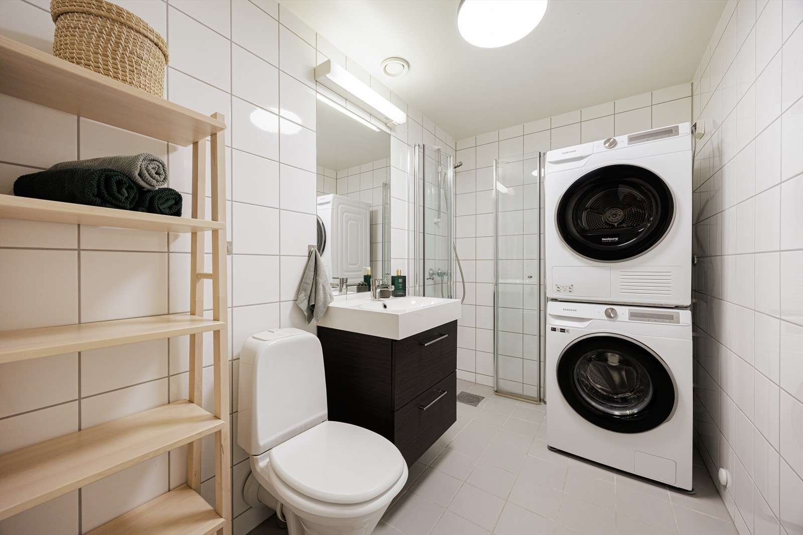 Flislagt og funksjonelt baderom med gulvvarme for ekstra komfort. Badet er innredet med benkeskap med glatte fronter og heldekkende servant, samt innfliset speil over. Galleribilde