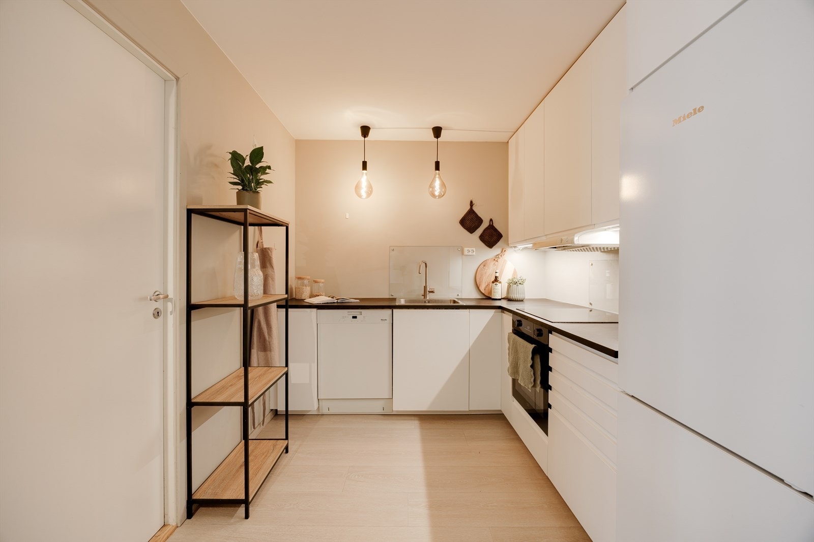 Over platetopp og kum er det montert glassplate som både beskytter veggen og gir et tidsriktig uttrykk. Innredningen har god skap- og benkeplass, nedfelt kum i rustfritt stål og ventilator. Galleribilde