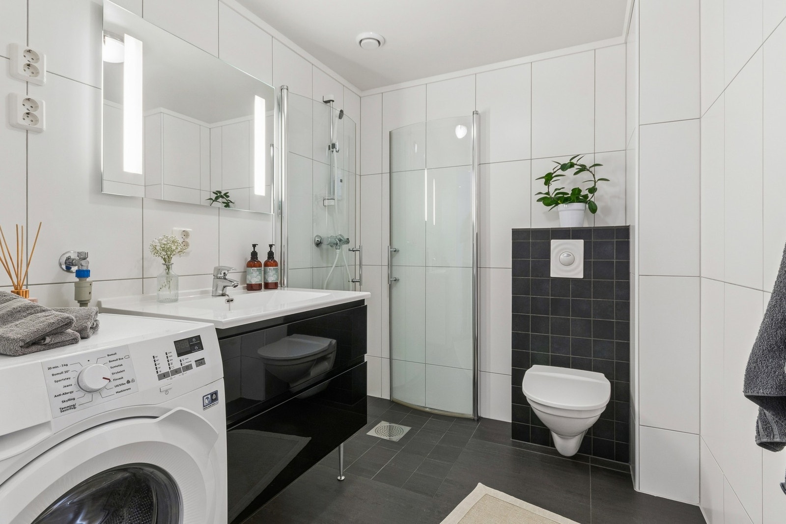Flislagt bad/vaskerom med dusjhjørne, vegghengt WC og servantseksjon. Opplegg for vaskemaskin og varmekabler i gulv. Galleribilde