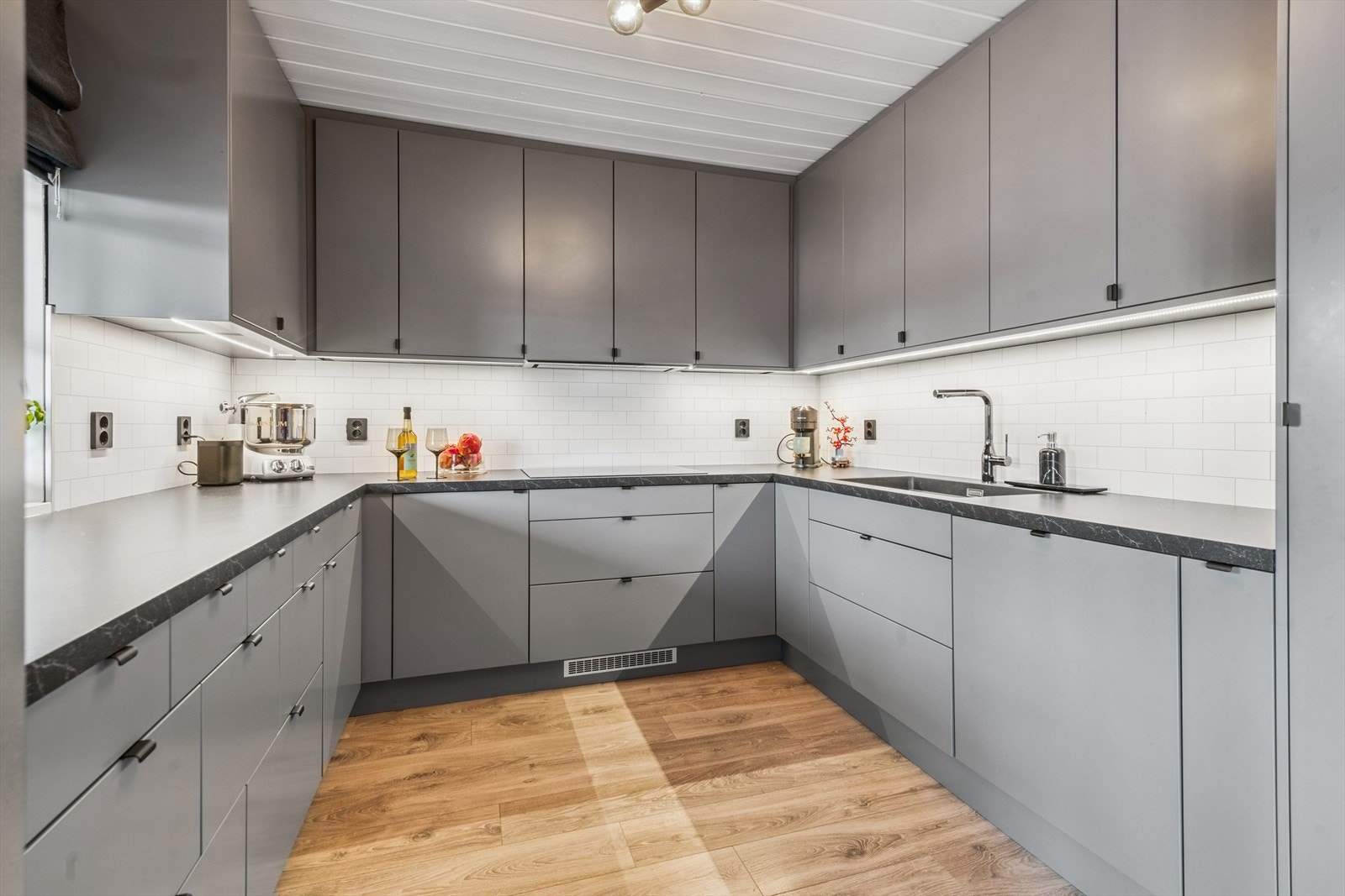 Grått kjøkkeninnredning fra 2021 med slette fronter og laminert benkeplate. Galleribilde