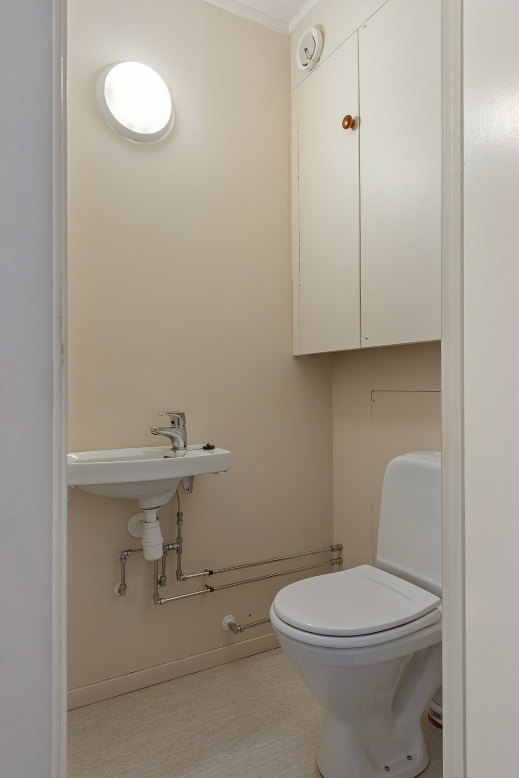 Toalettrom med vinylbelegg på gulv. Malte plater på vegger. Rommet har servant med ett- greps blandebatteri. Wc. Galleribilde