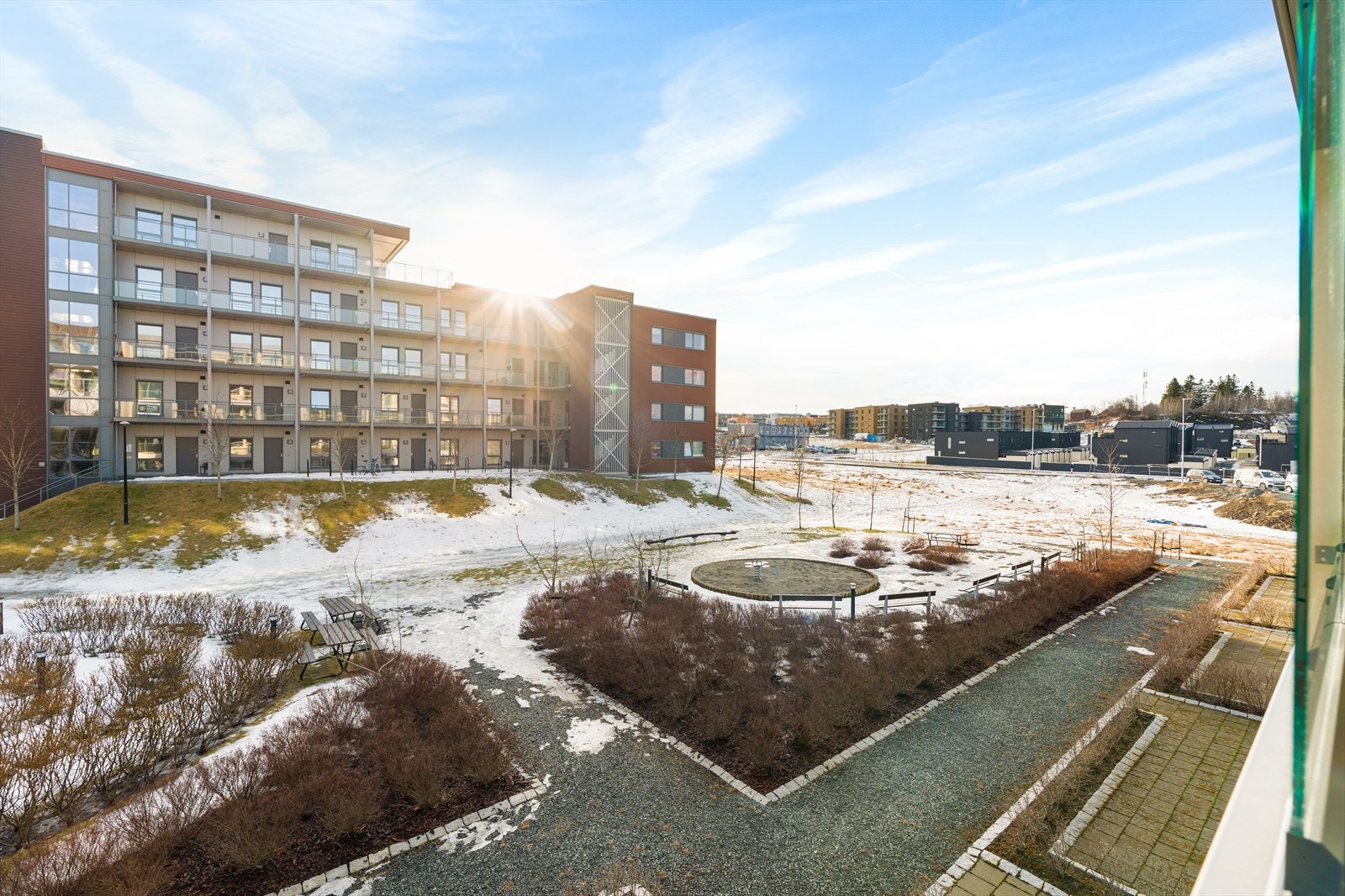 Balkongen vender mot rolige og store fellesareal i sameiet. Her er det god avstand mellom boligblokkene, og grønn beplantning som vokser seg fin på sommerstid. Galleribilde