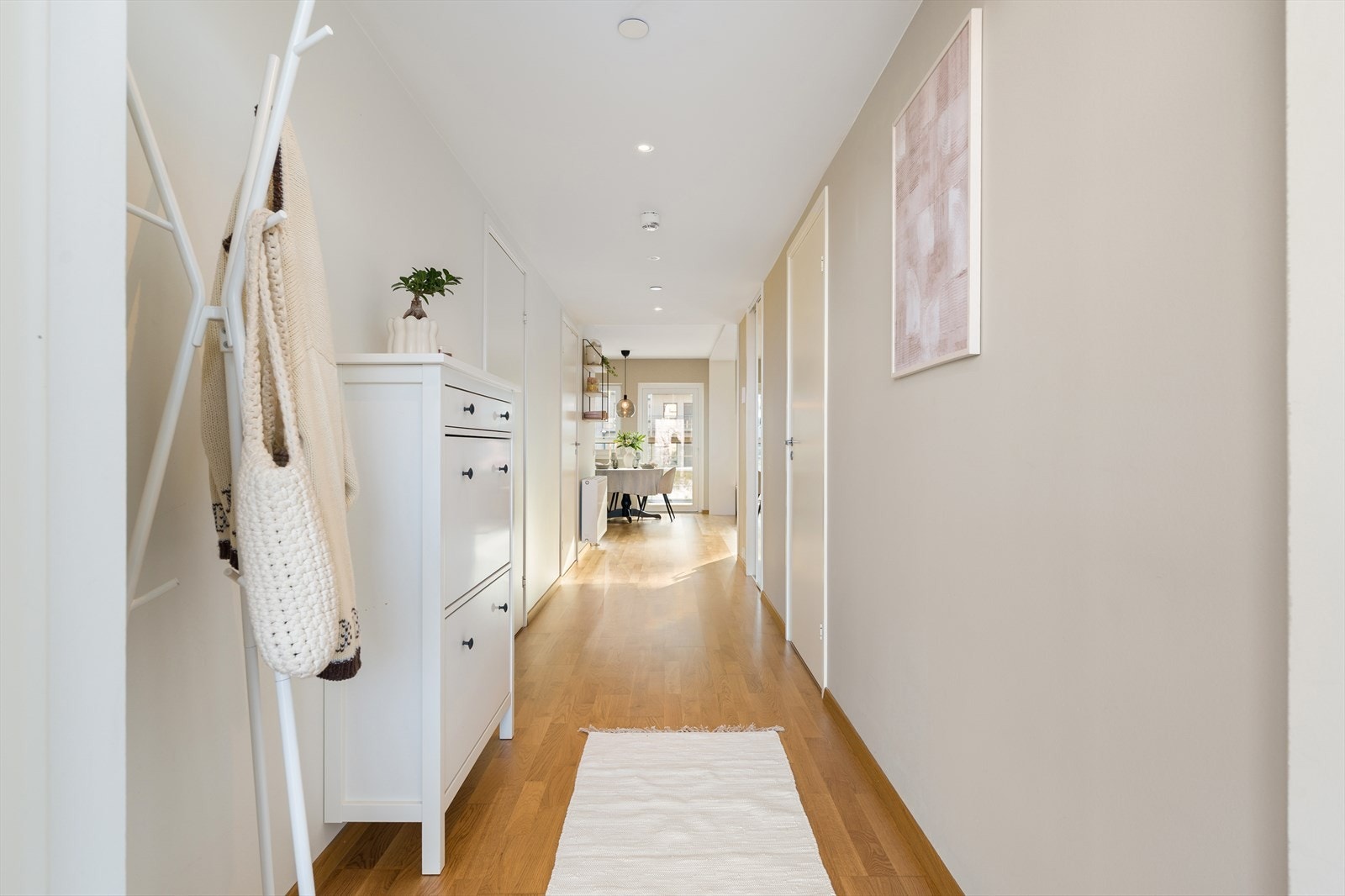 Her kommer man inn til en innbydende entré som utgjør hjemmets førsteinntrykk. Gangen er innredet med en plassbygd skyvedørsgarderobe for oppbevaring av klær og sko. Nåværende eier har også innredet med skoskap og stumtjener. Galleribilde