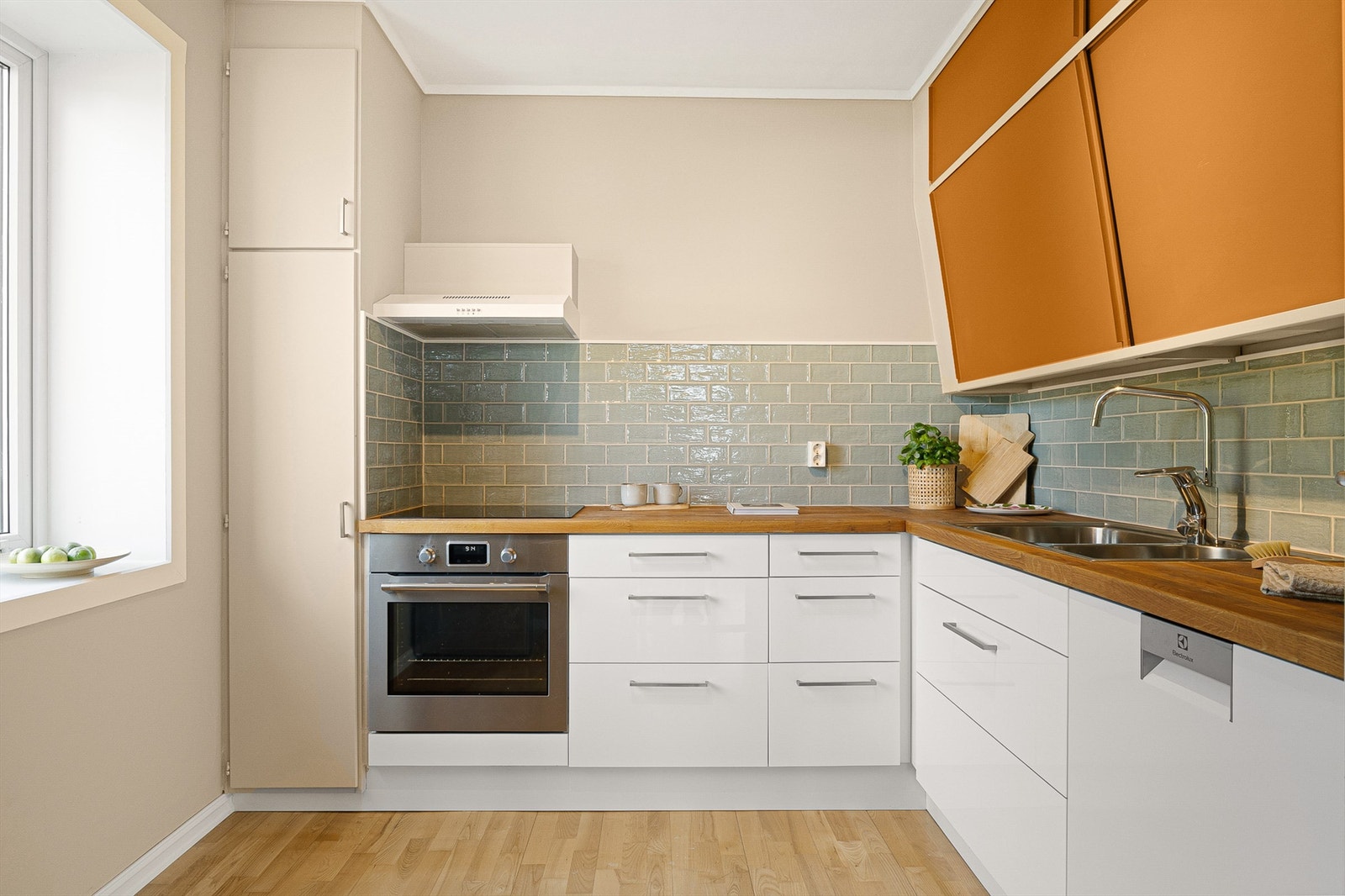 Fin kjøkkeninnredning med glatte fronter og benkeplate av tre. Kjøkkenet ble oppgradert i 2025 med maling, nye fliser og ny ventilator. Galleribilde