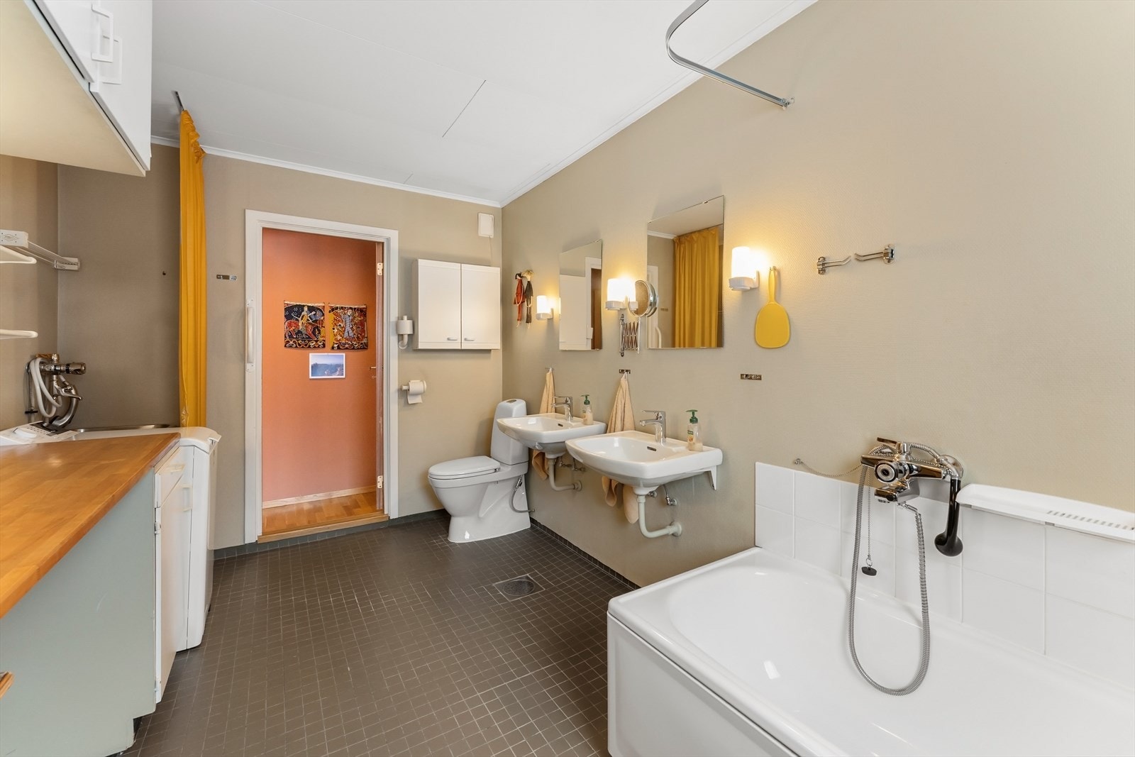 Badet har 2 servanter med speil, gulvmontert toalett, badekar, utslagsvask og benkeinnredning med opplegg for vaskemaskin. Galleribilde