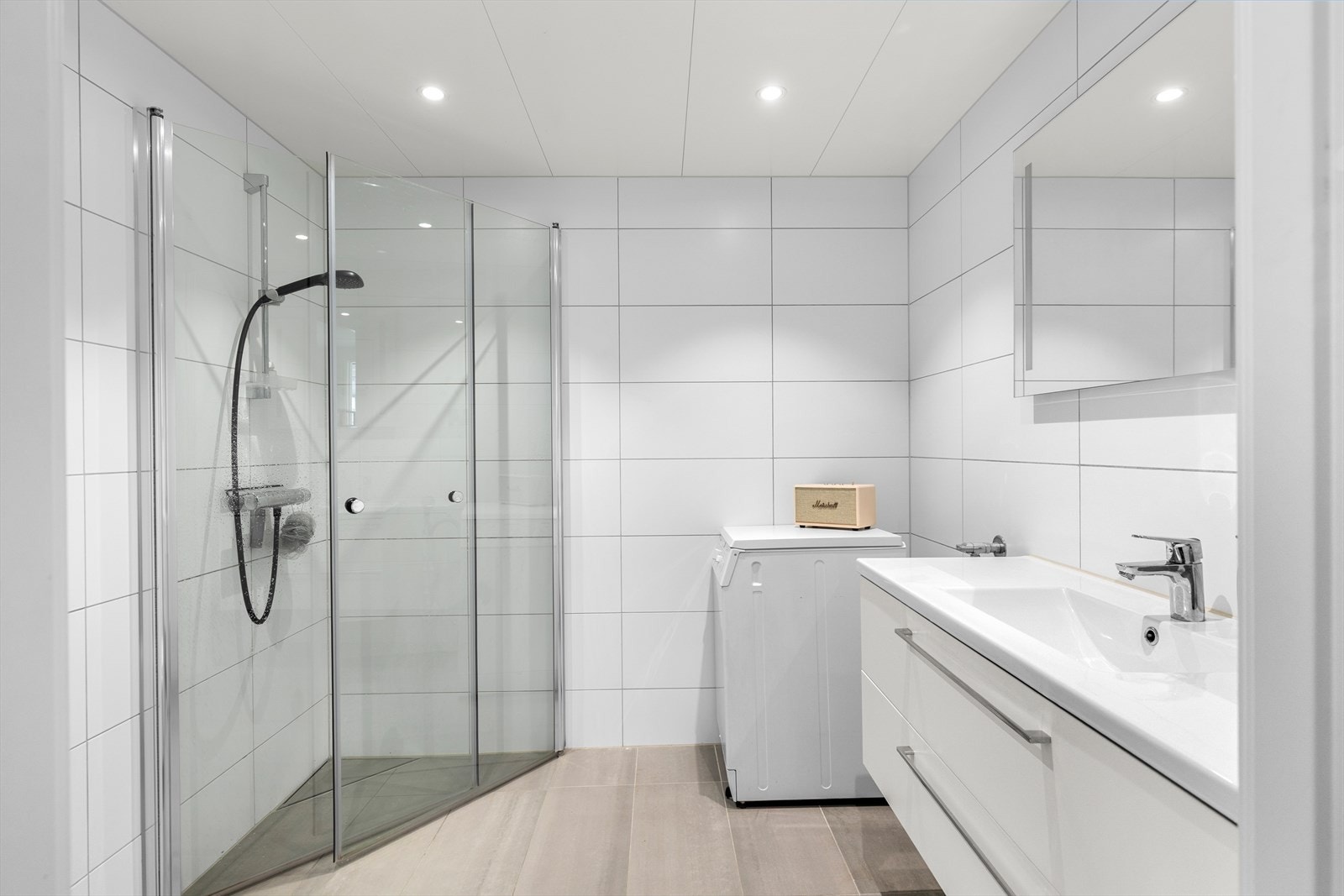 Pent flislagt baderom på 4,5 kvm. Her får du flott servant med underskap, dusjhjørne, vegghengt WC og opplegg for vaskemaskin Galleribilde