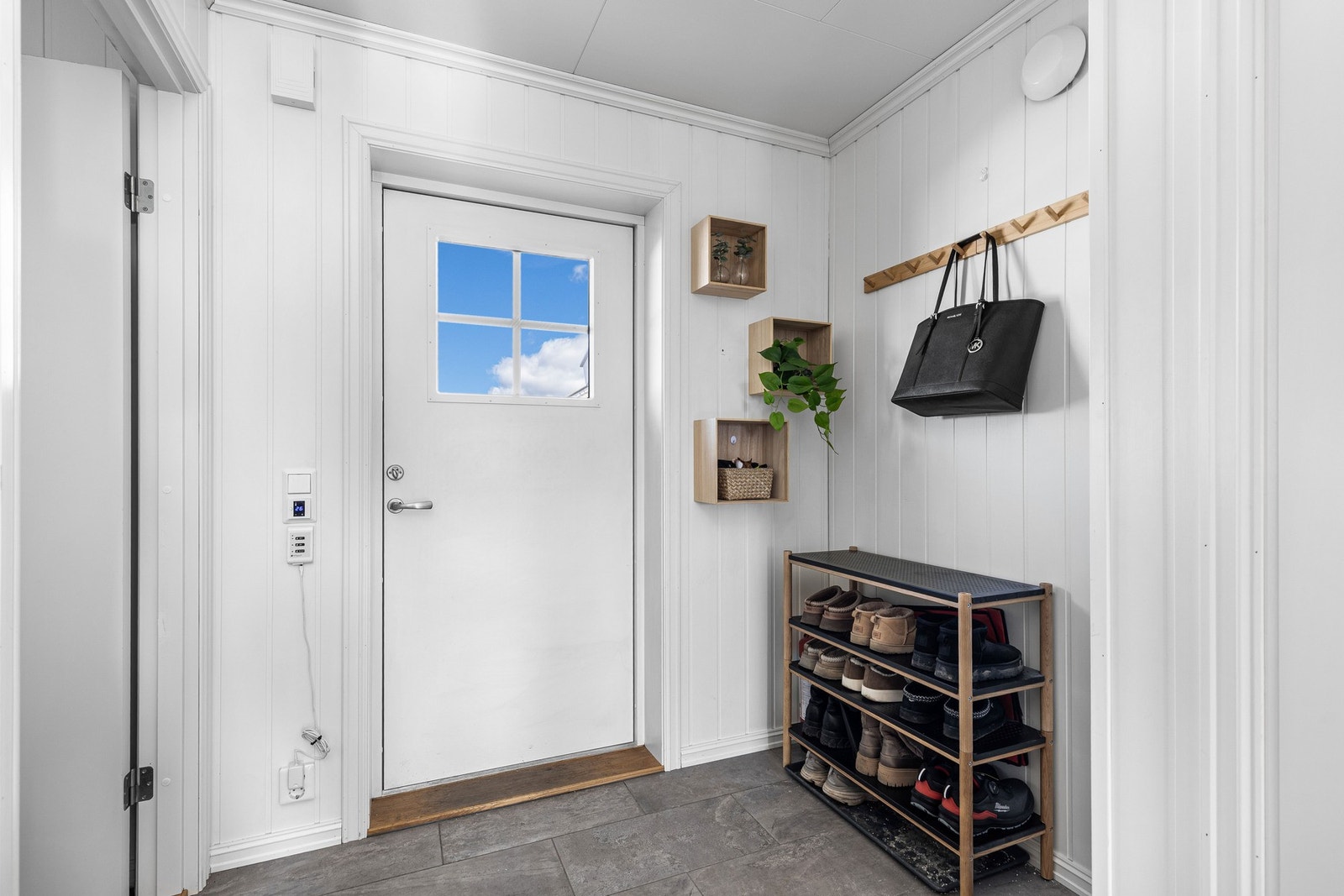 Innenfor døren møtes man av en lys og innbydende entré med flislagt gulv og varmekabler, samt hvitmalte vegger. Galleribilde