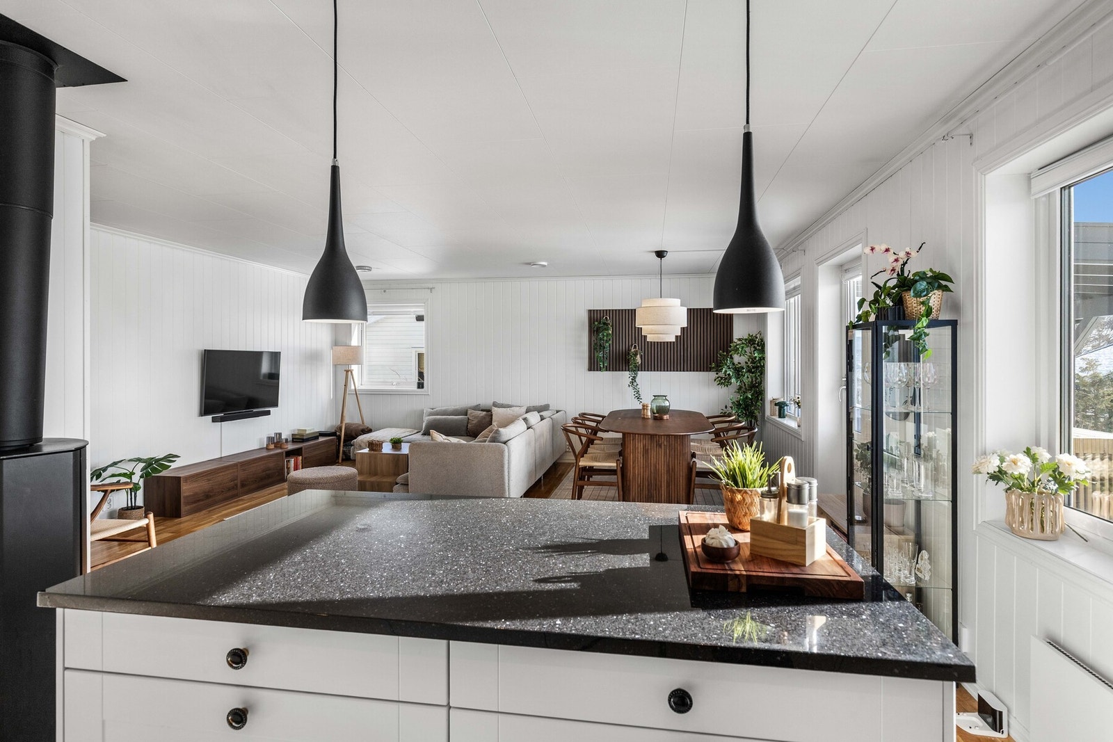 En kjøkkenøy danner en naturlig avgrensning mot stuen og gir samtidig mulighet for en hyggelig sitteplass med barstoler. Galleribilde