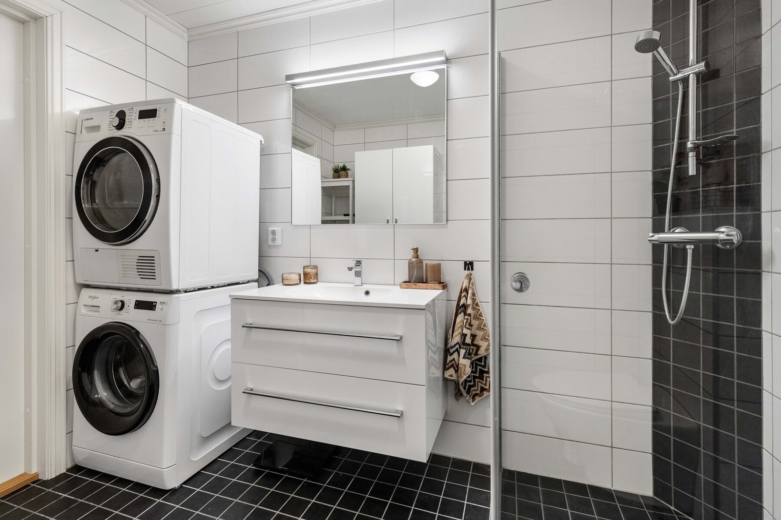 Badet er pent flislagt med sorte fliser på gulvet og hvite fliser på veggene. Galleribilde