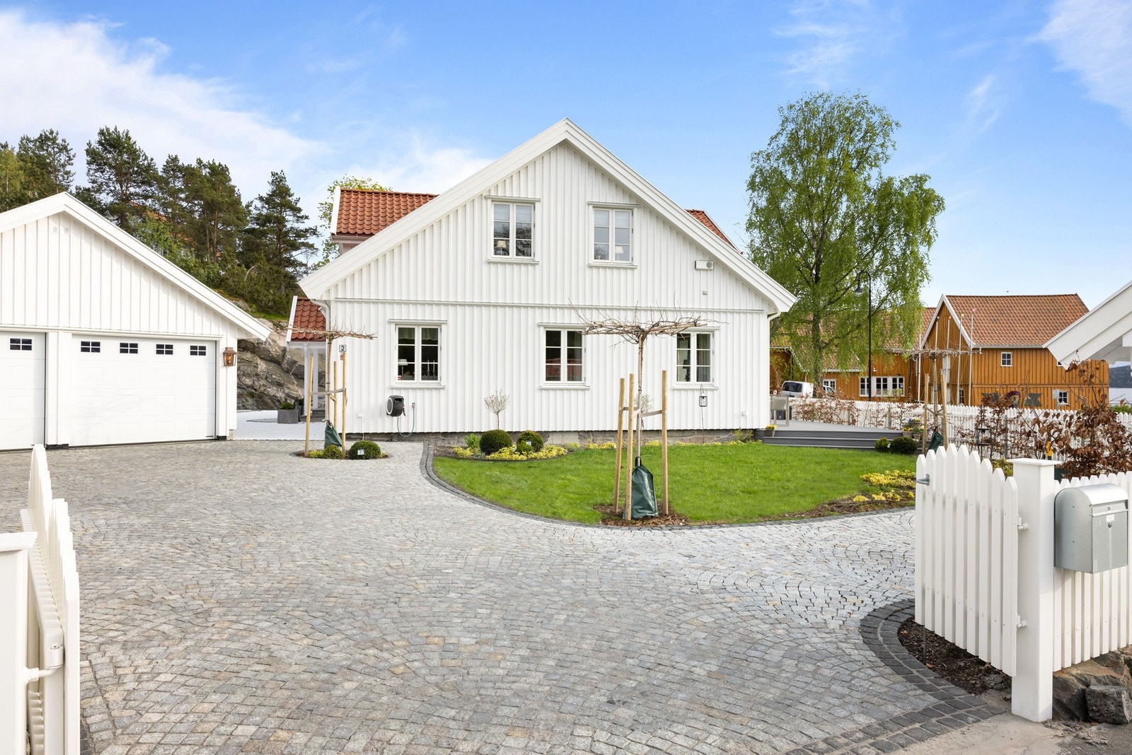 Representativ innkjørsel med brosteinsbelagt gårdsplass og adkomst til dobbelgarasje. Galleribilde