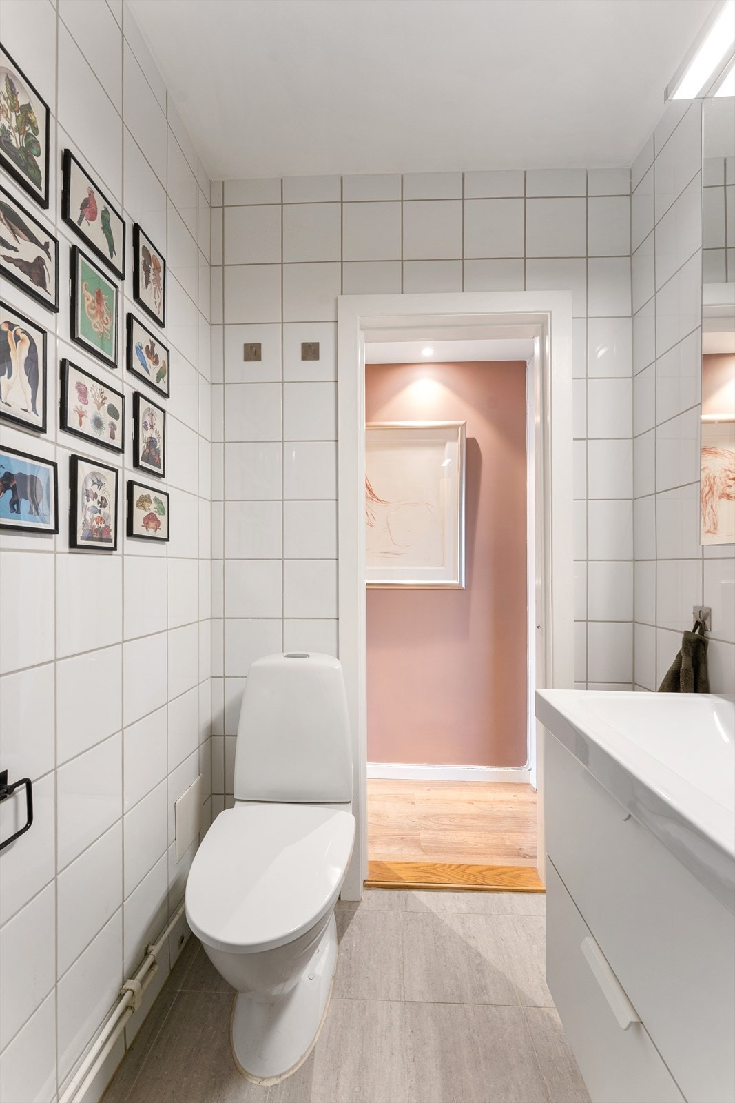 Badet er innredet med baderomsmøbel bestående av benkeskap med glatte fronter og veggskap med speilfronter. Videre inneholder badet dusj med innfellbare dører i herdet glass, servant, gulvstående toalett og opplegg for vaskemaskin. Galleribilde