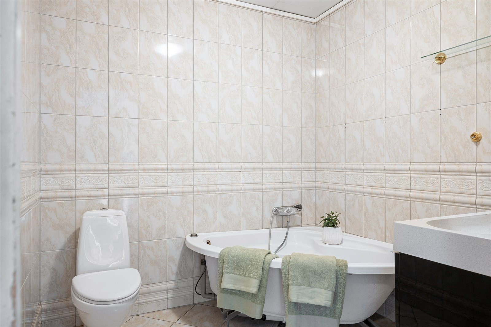 Badet har flislagt gulv med varmekabler, flislagte vegger og malt takess i taket. Galleribilde