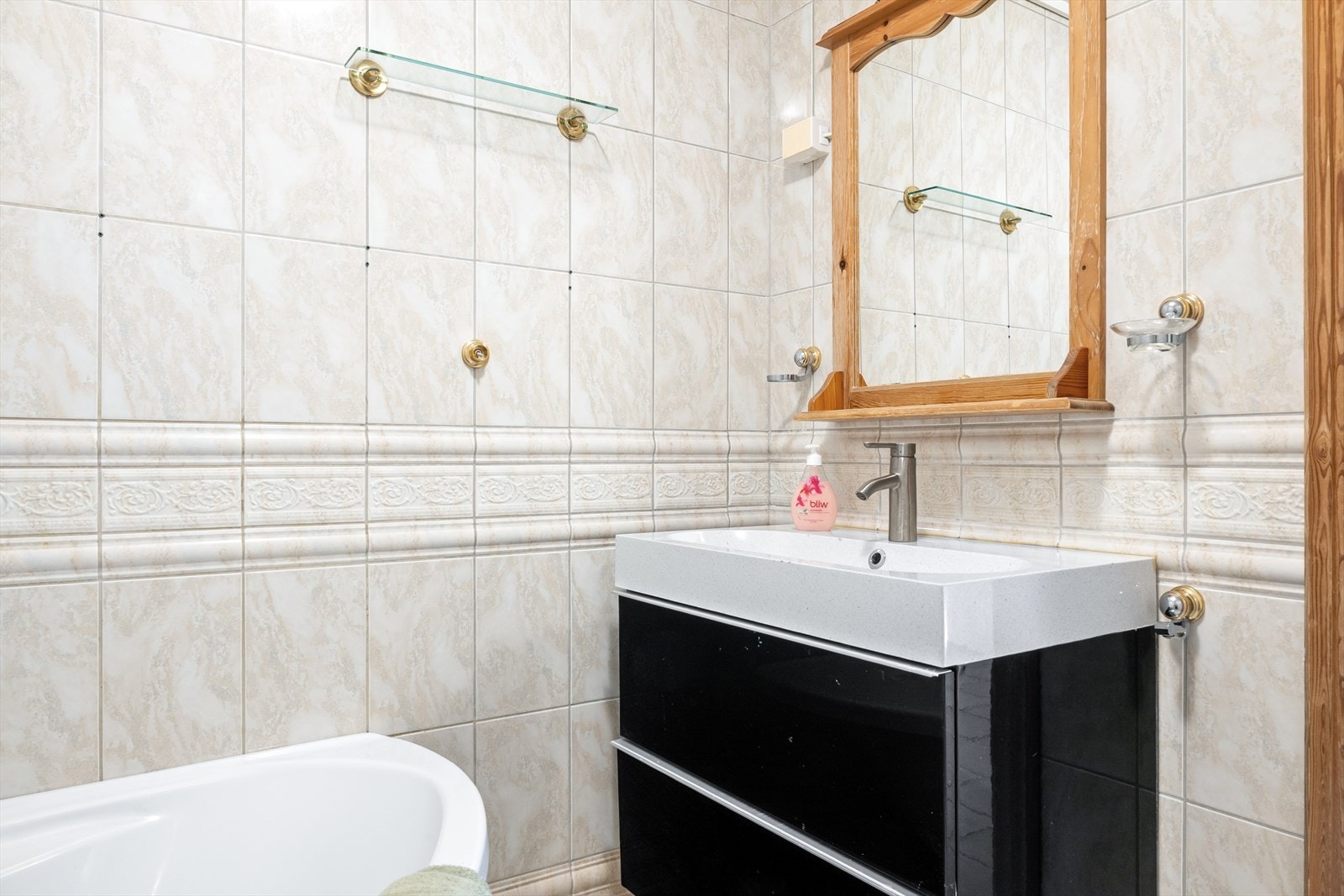 Det er innredet med vegghengt baderomsmøbel med servant, frittstående toalett og hjørnebadekar. Galleribilde