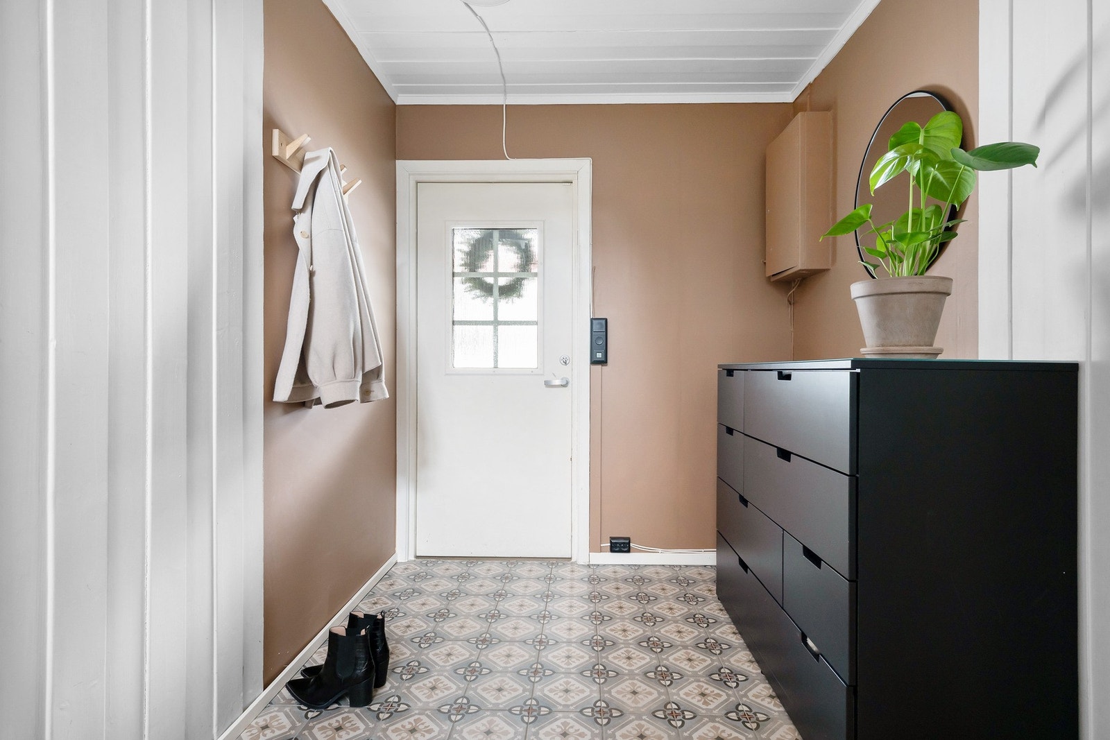 Innbydende entré med praktiske fliser på gulv og god plass til oppbevaring av yttertøy og sko Galleribilde
