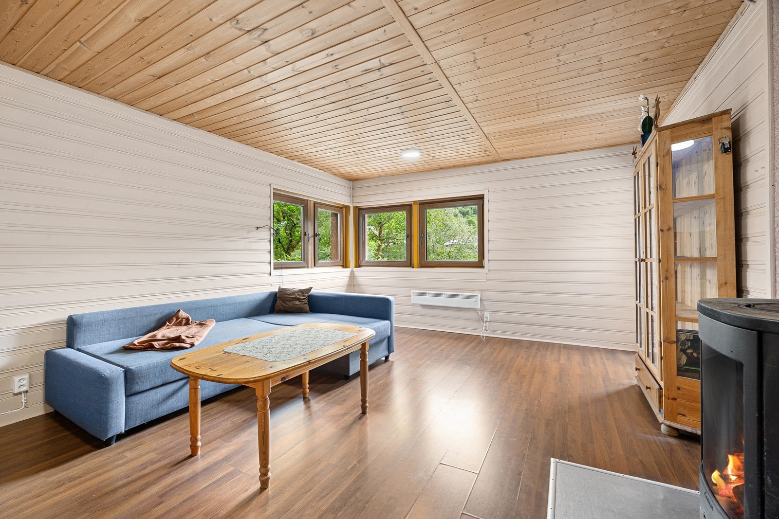 Koselig stue på 19,2 m². Legg merke til peisovnen, som kan varme opp rommet på de kjøligere dagene. Også praktisk med utgang fra stue til terrasse og hage Galleribilde