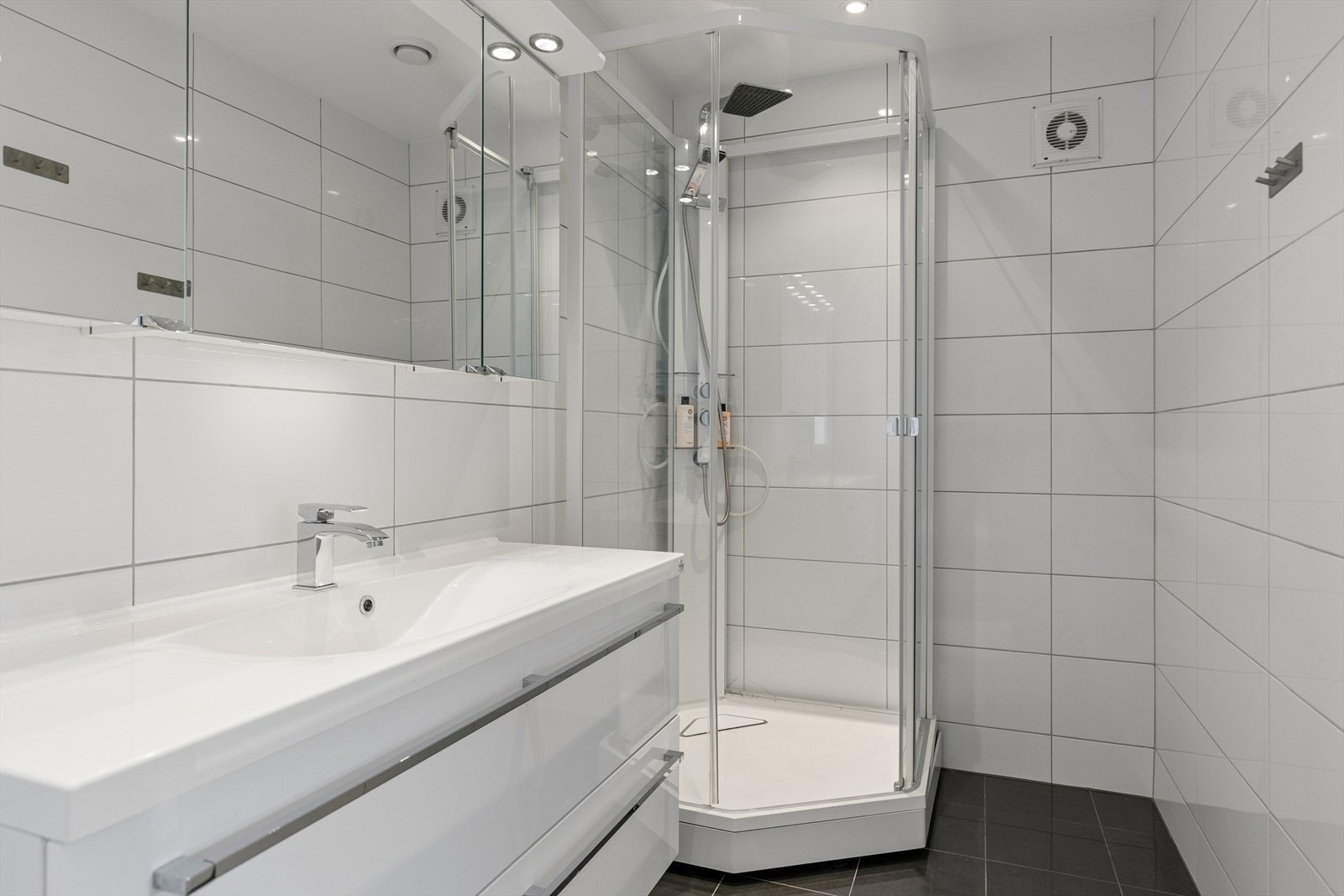 Delikat bad med baderomsinnredning, dusjkabinett og veggmontert toalett. Galleribilde