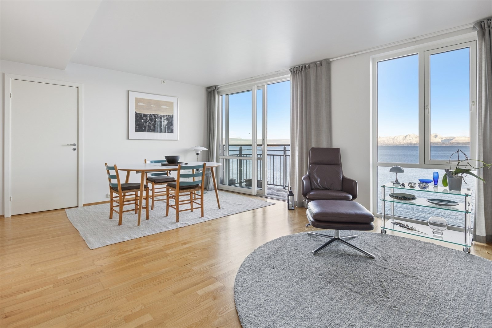 De store vindusflatene og den brede skyvedøren ut til balkongen slipper inn rikelig med naturlig lys gjennom hele dagen og skaper en lys, åpen og innbydende atmosfære i stuen. Galleribilde