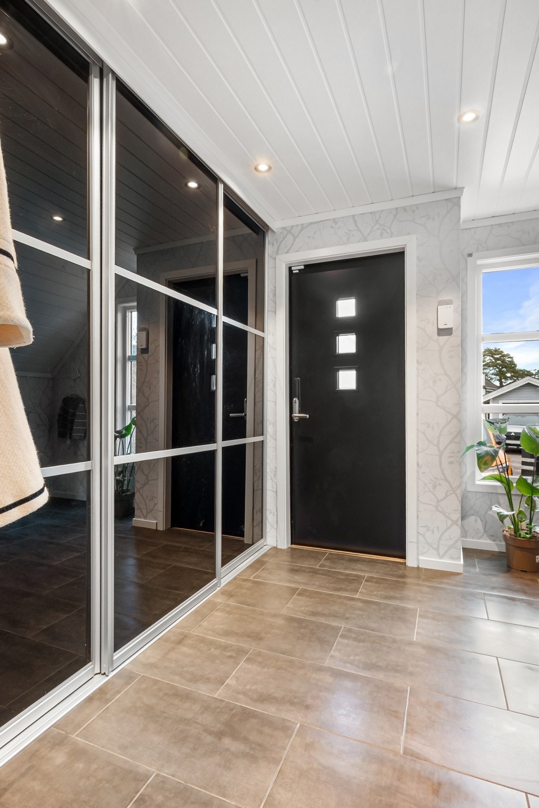 Entréen er romslig og praktisk utformet med flislagt gulv med varmekabler og downlights i himling. Her er det god oppbevaringsplass i stor skyvedørsgarderobe Galleribilde