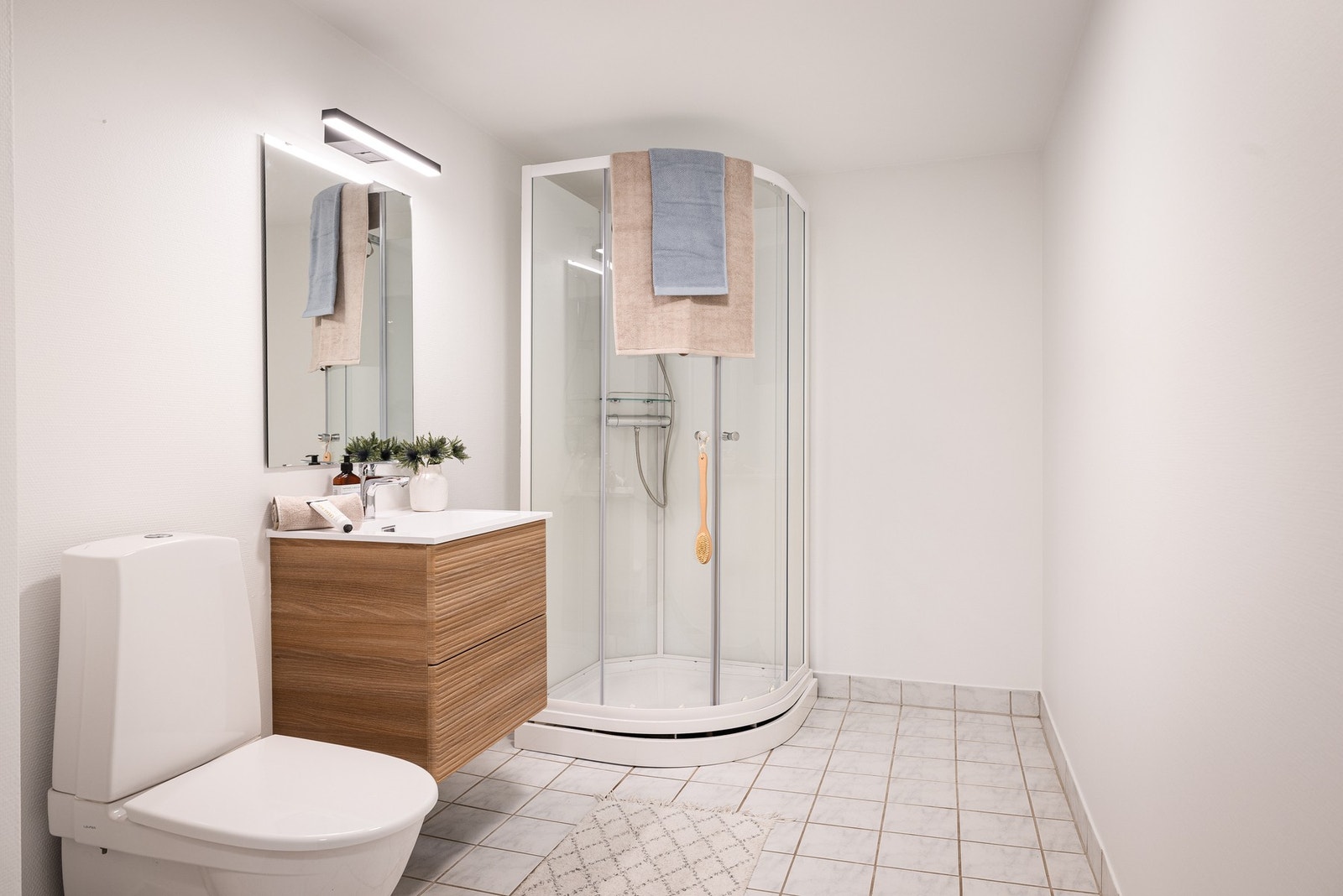 Bad fra 1995 med dusjkabinett fra 2026 som fører vannet direkte til sluk. Galleribilde