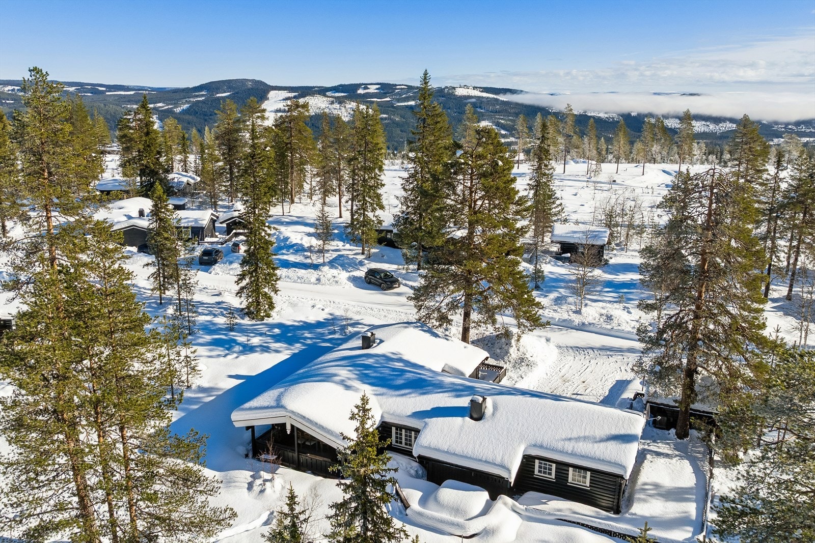 En solid fritidsbolig oppført i tradisjonell stil med 6" håndlaftet tømmer, med en usjenert beliggenhet i et etablert hytteområde med umiddelbar nærhet til skog og mark. Galleribilde