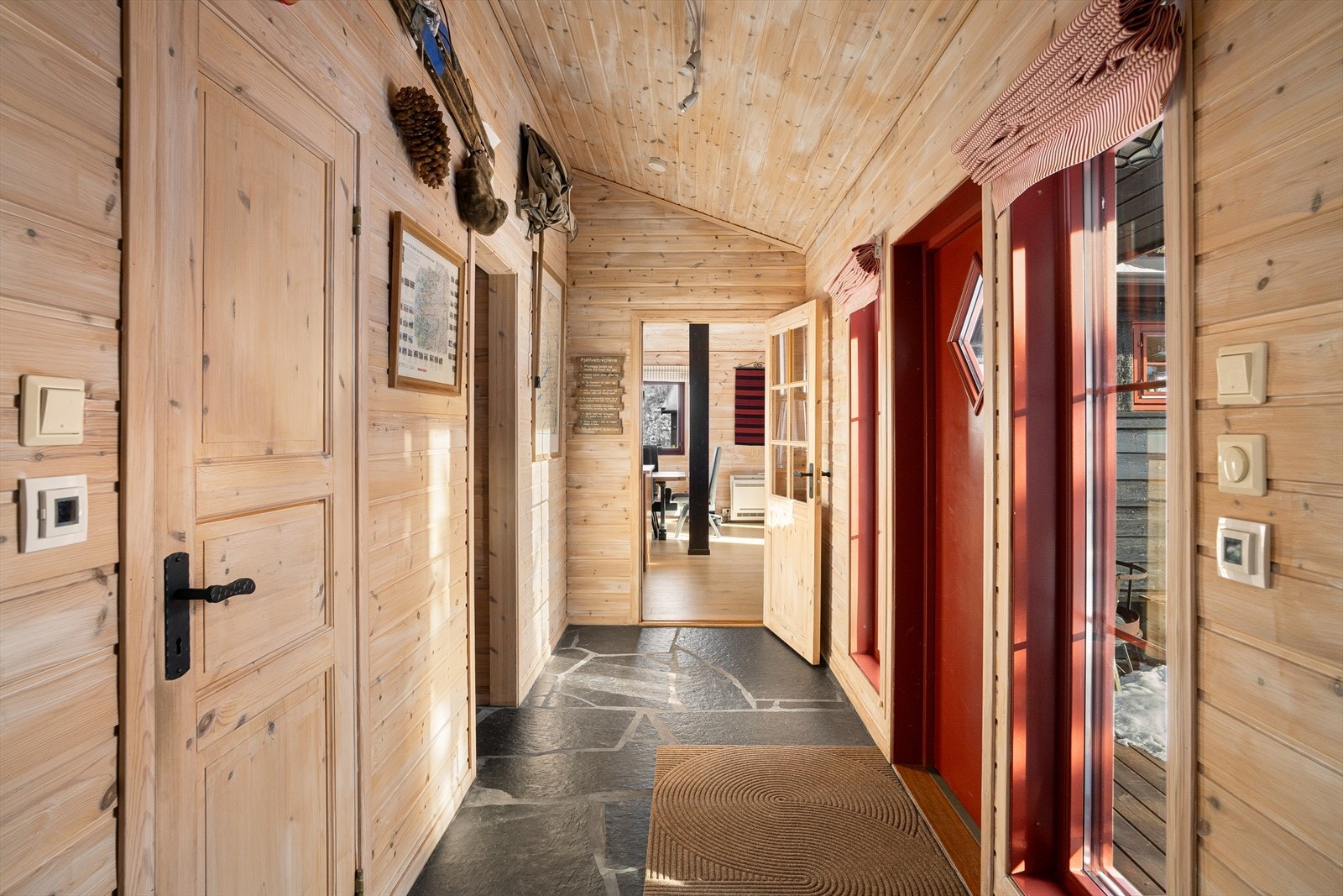 Når du trer inn i boligen møtes du av en romslig gang med slitesterkt skifergulv med varmekabler og mellomgang som fordeler hyttens ulike rom på en god måte. Vinduene ved inngangsdøren slipper inn naturlig lys og skaper en lys og inviterende atmosfære. Galleribilde