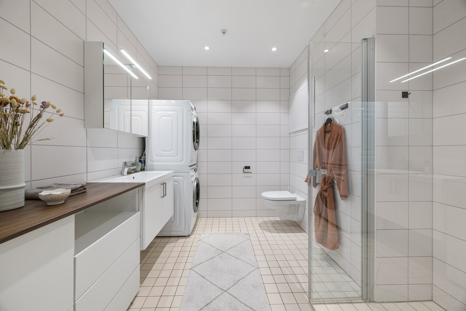 Delikat, flislagt bad med elektriske varmekabler, dusjnisje og opplegg for vaskemaskin. Galleribilde