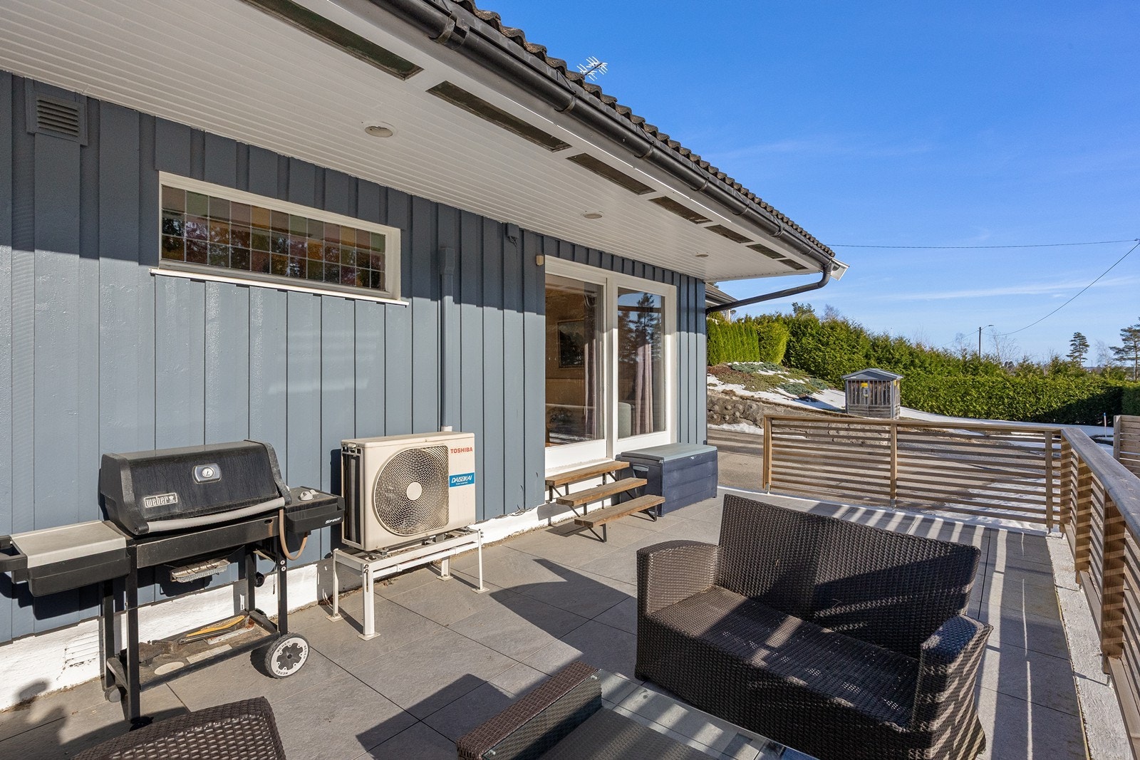 Flislagt terrasse med rekkverk i tre gir et solid uteområde. Galleribilde