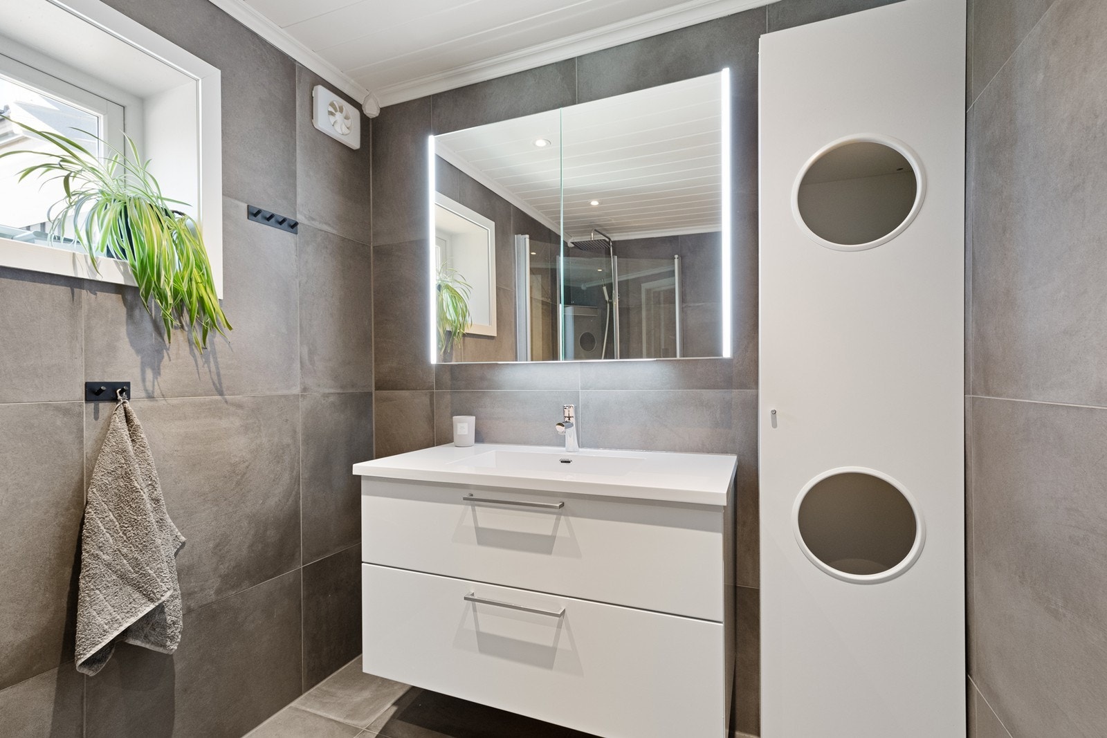 Servantskap med speil og lys gir praktisk baderomsløsning. Galleribilde