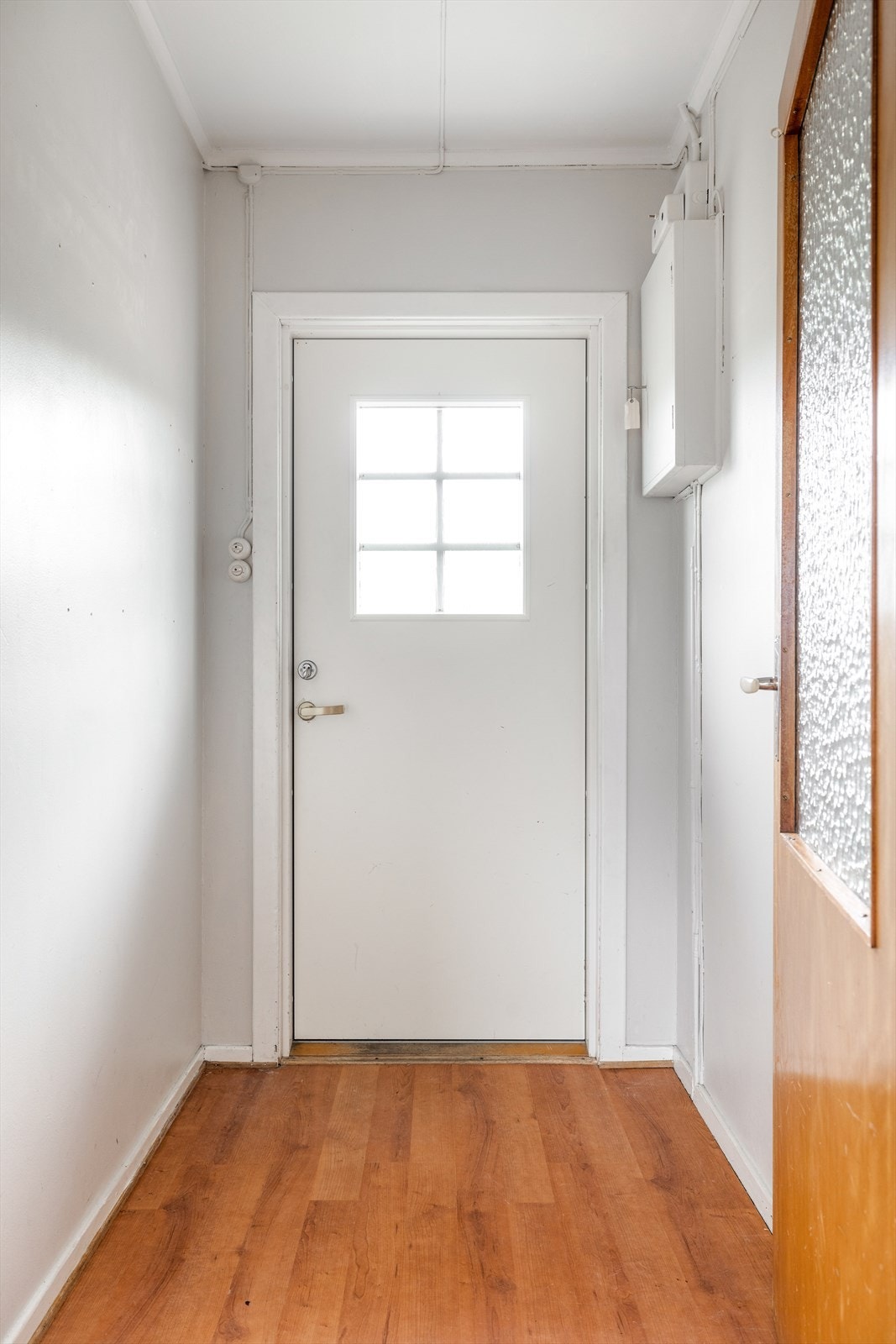 Liten og lys entré i hovedetasjen, hvor boligens sikringsskap er montert. Galleribilde