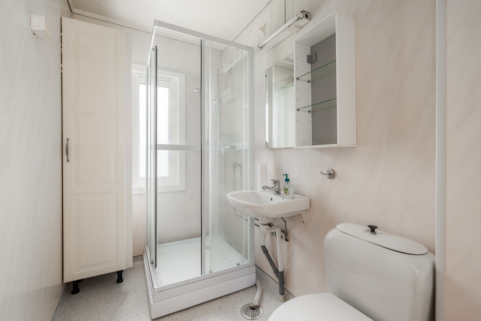 Eldre bad med toalett, dusjkabinett, servant på vegg, hylle og speil med overlys. Det er byttet varmeovn, nye stikk og taklampe i 2023. Nytt vindu i 2021. Galleribilde