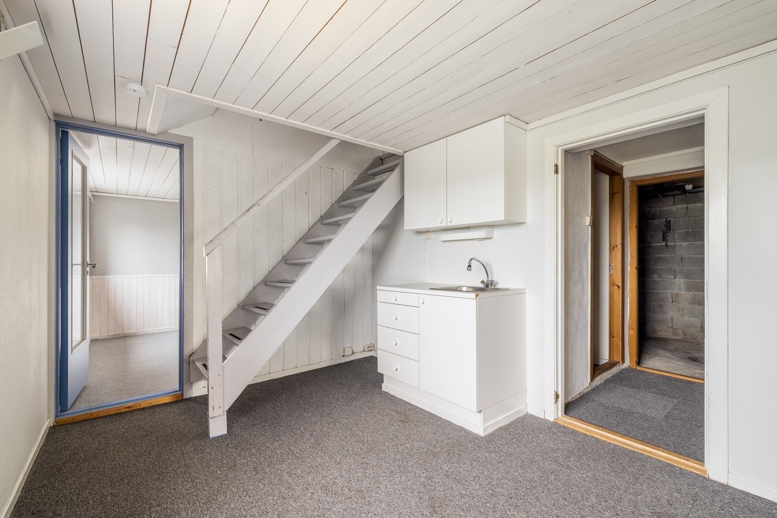 Enkel kjøkkeninnredning i underetasjen, med over- og underskap. Laminat benkeplate med nedfelt oppvaskkum i rustfritt stål. Galleribilde