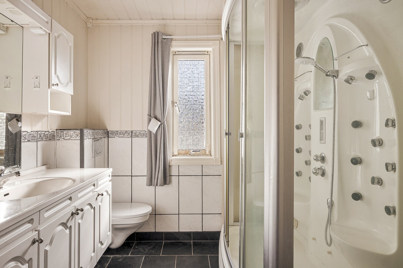 Badet er innredet med servant i møbel, vegghengt toalett og dusjkabinett. Galleribilde