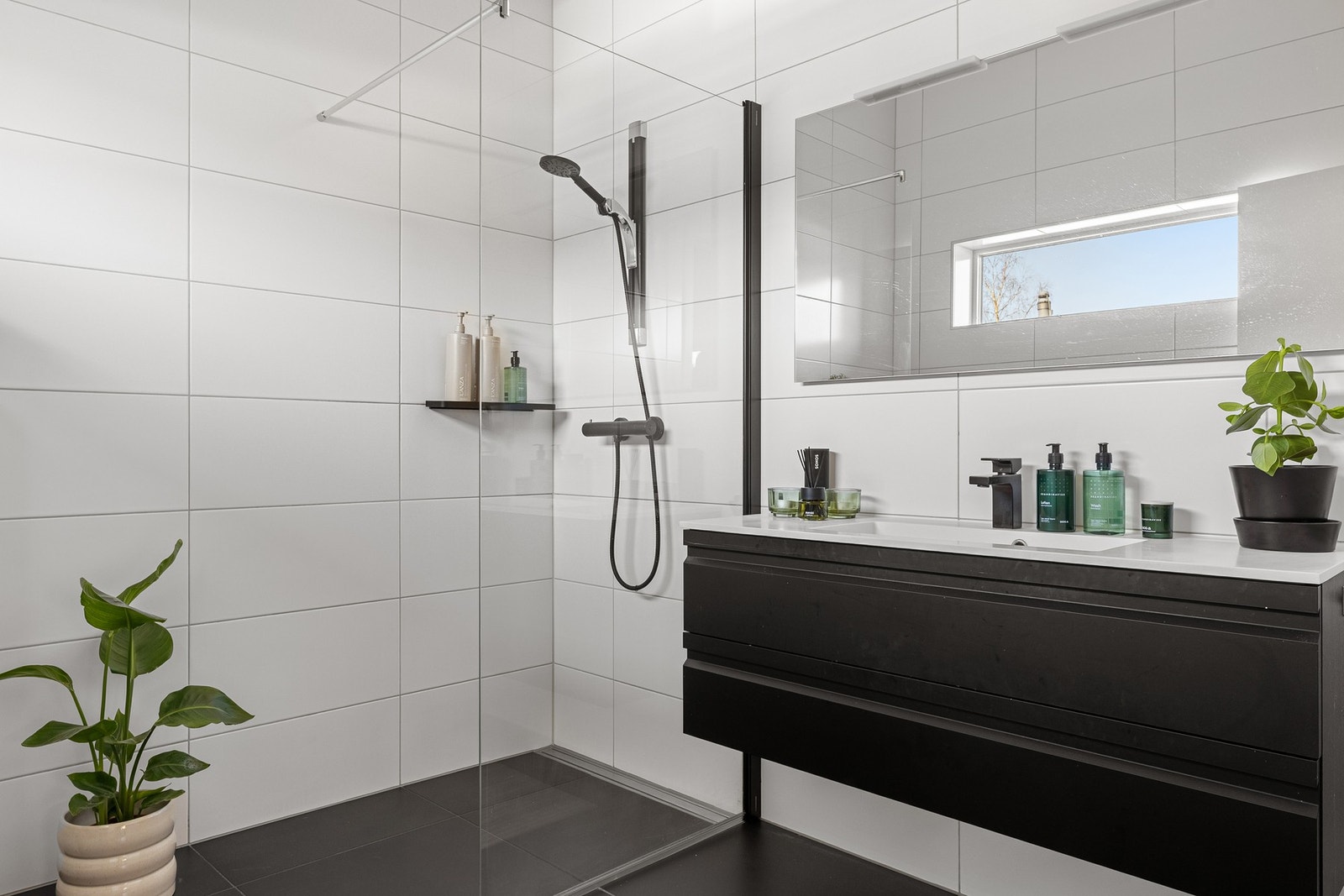 Det er innredet med vegghengt toalett, dusjhjørne med dusjvegg og baderomsmøblement med speil og belysning. Galleribilde