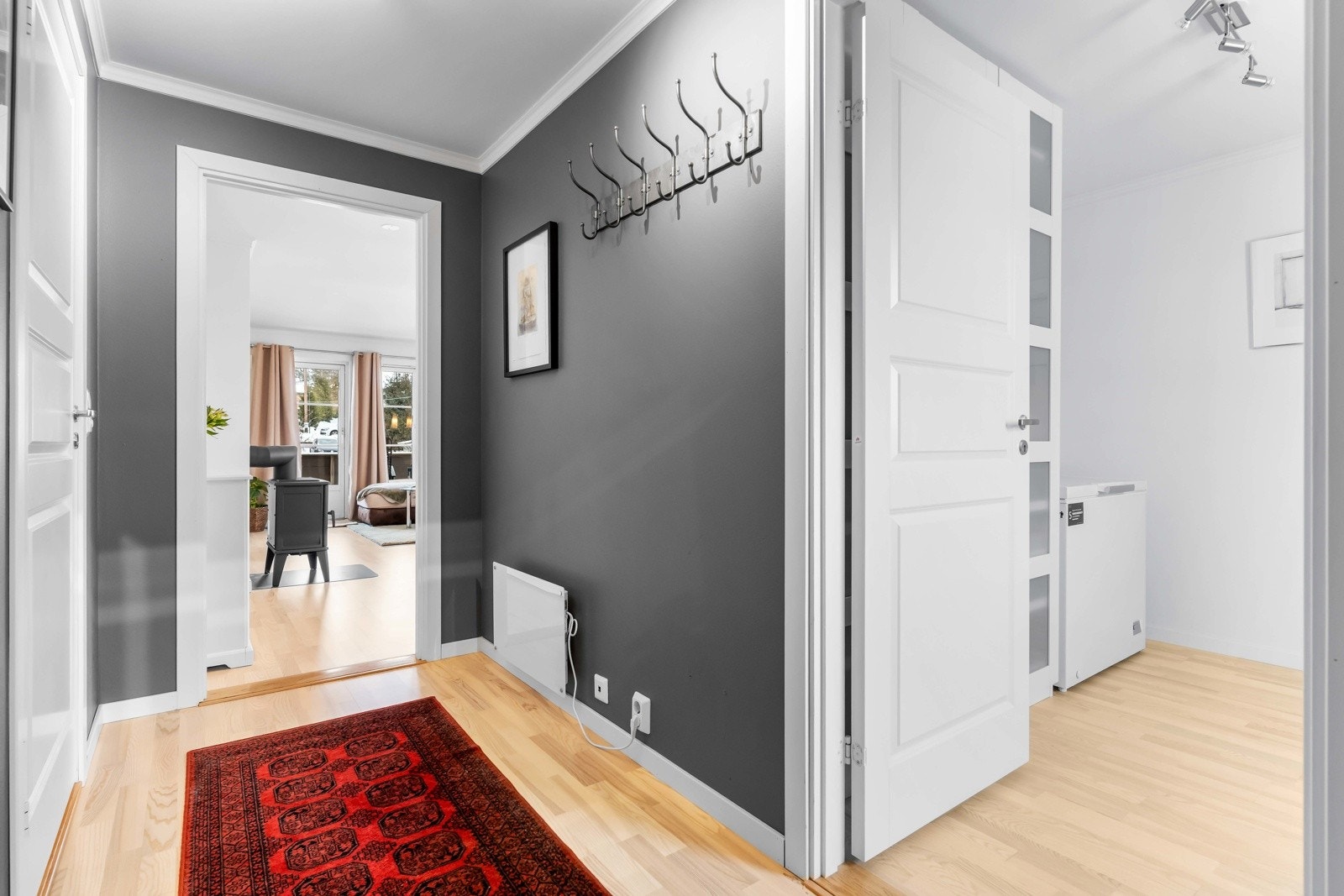 Avlang og romslig entré med trestavsparkett på gulv. Veggene har tidsriktige farger som gir et nøytralt og moderne uttrykk. God plass til garderobeløsninger og praktisk oppbevaring. Galleribilde