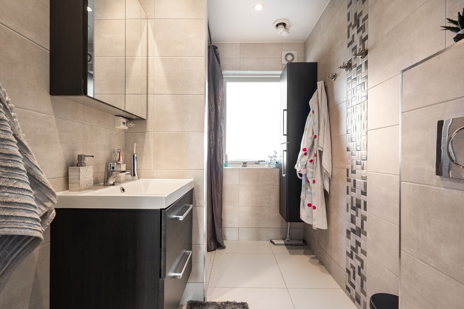 Pent flislagt bad med veggfestet wc, dusjnisje og flotte baderomsmøbler Galleribilde